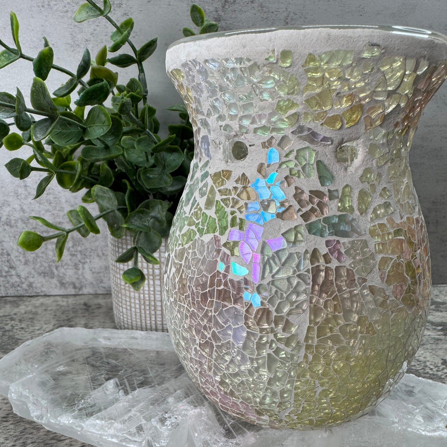 Mosaic-patterned vase with greenery on a textured surface