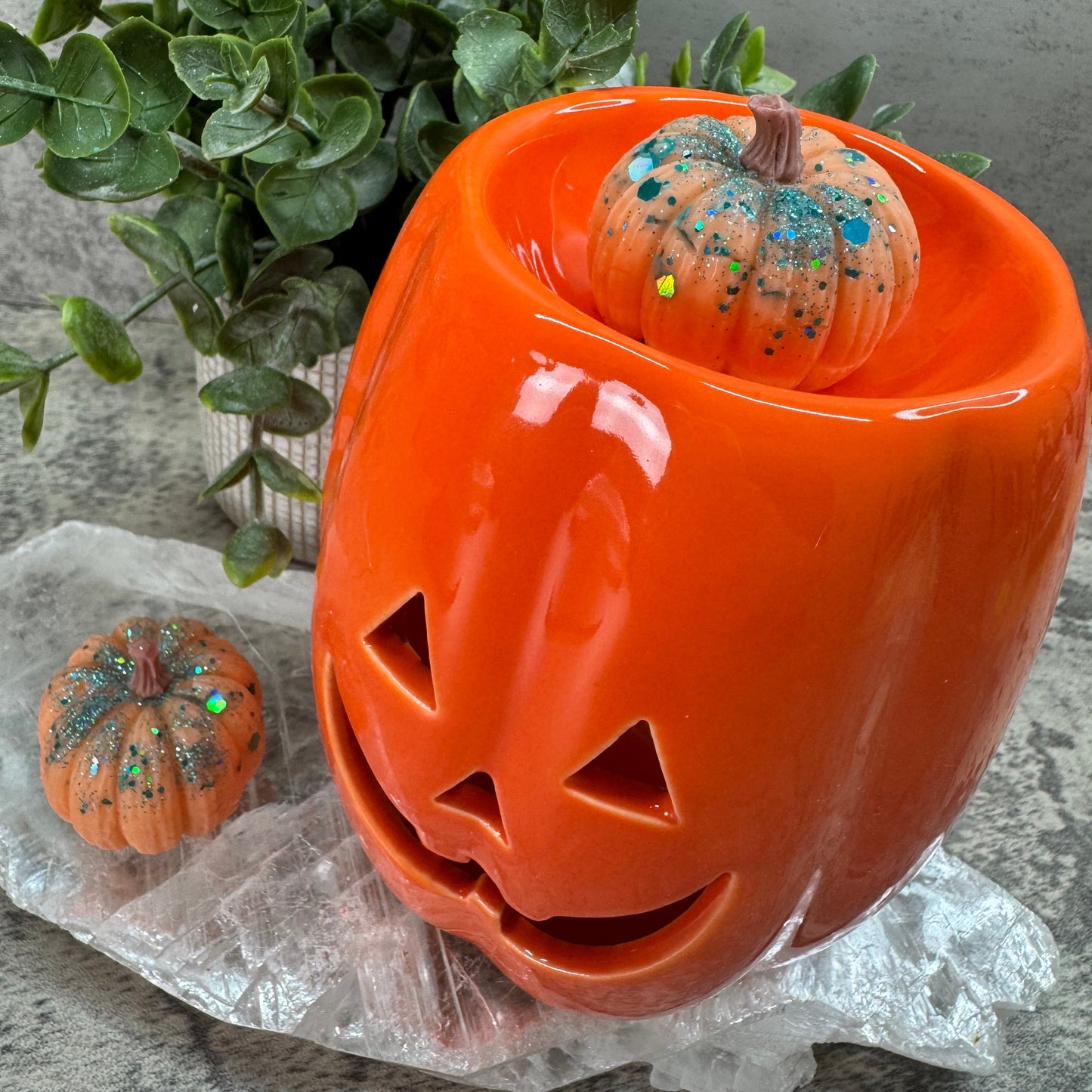 Orange ceramic pumpkin with a smaller decorative pumpkin inside on a gray surface.