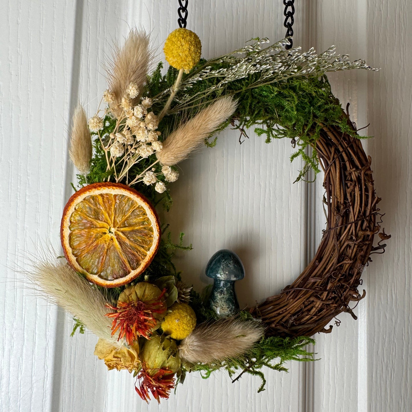 Decorative wreath with natural elements on a white wooden door