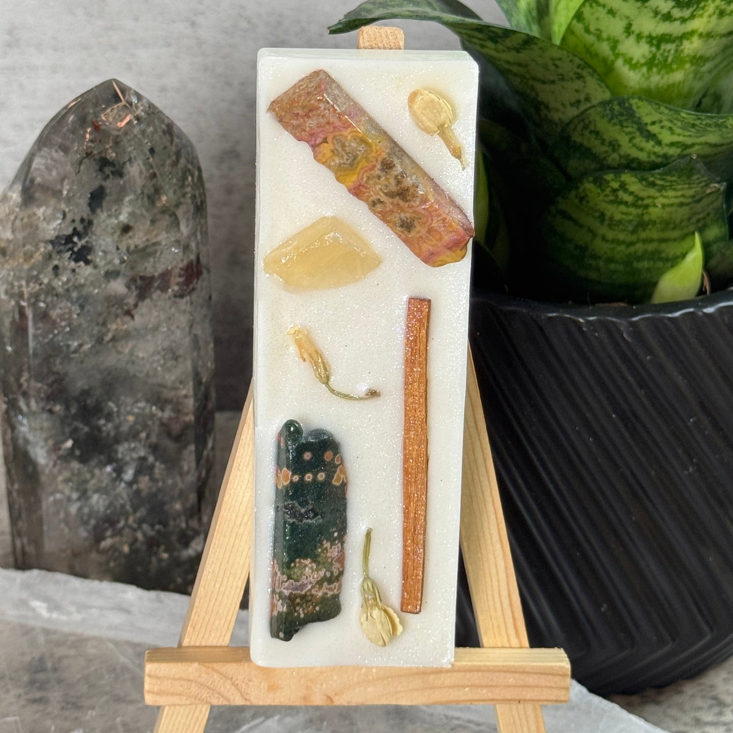 Decorative stone with embedded natural elements on a wooden stand, set against a neutral background.
