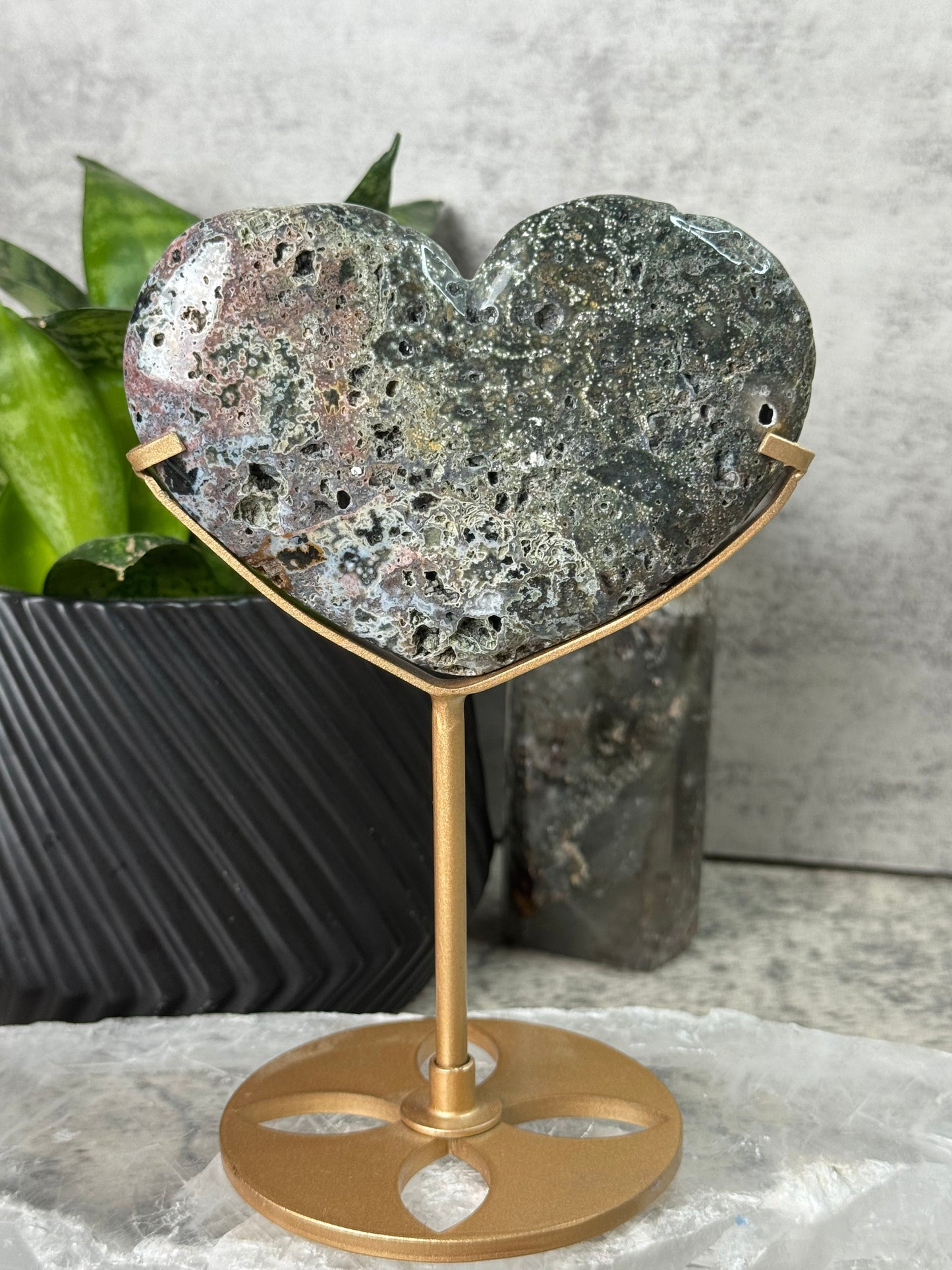 Decorative wall piece with gold frame and textured stone heart on a concrete surface.