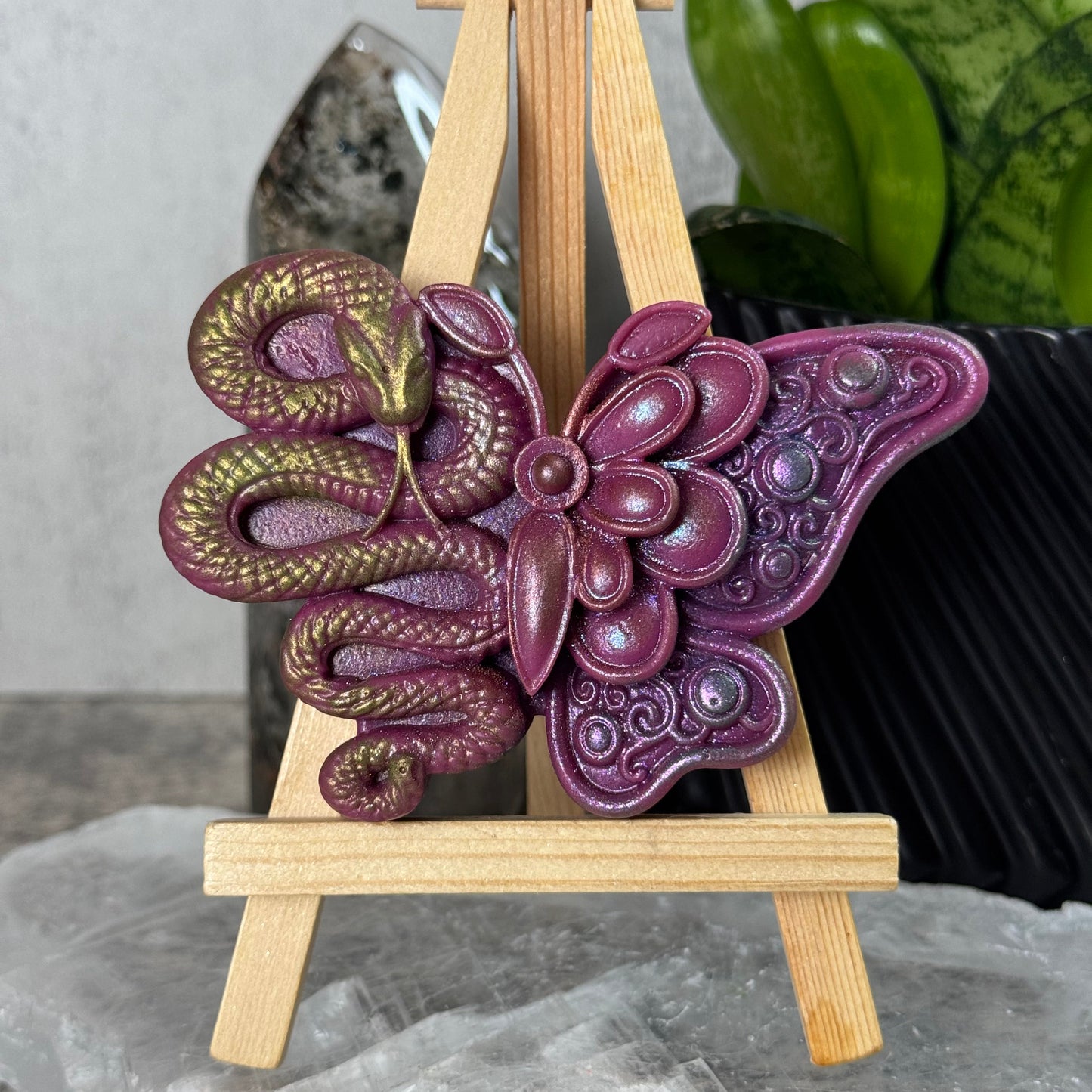 Purple butterfly-shaped decorative item on a wooden stand with a blurred background