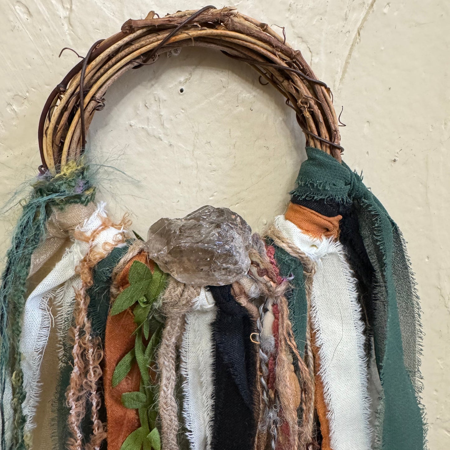 Textile art piece with natural materials on a neutral background