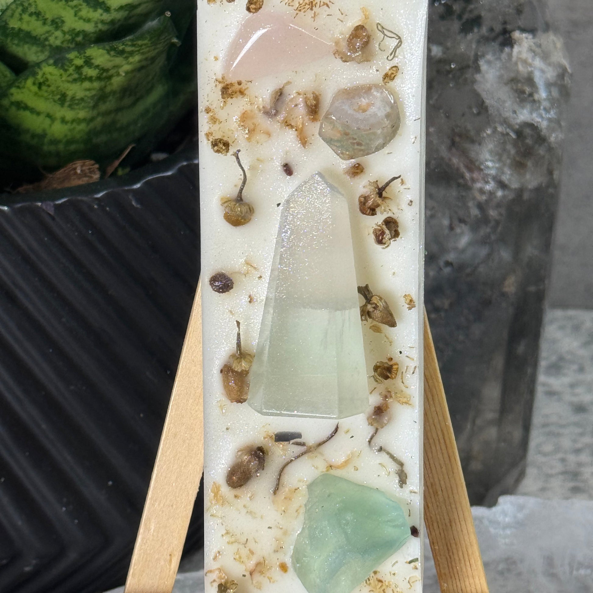 Decorative soap with natural elements on a wooden stand against a stone background
