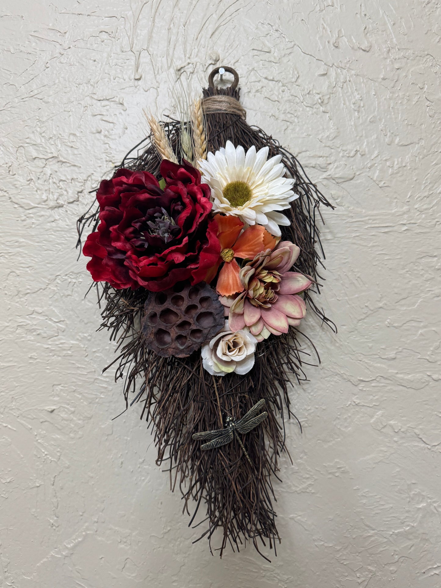 Decorative wall piece with flowers and feathers on a textured white background