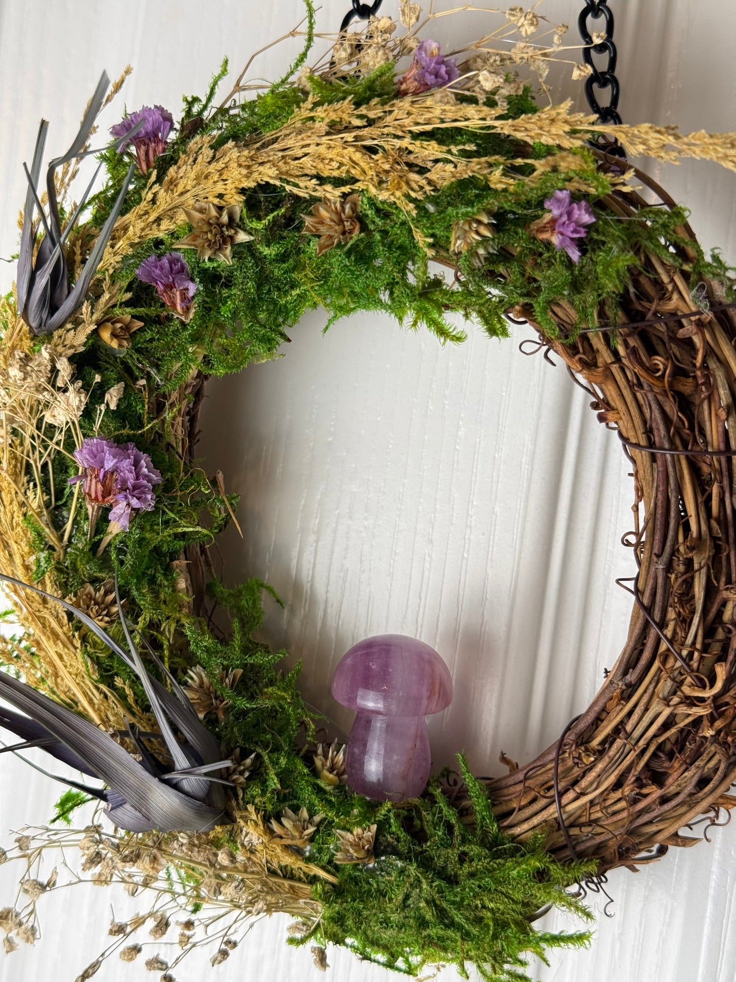 Wreath made of greenery and purple flowers on a white background