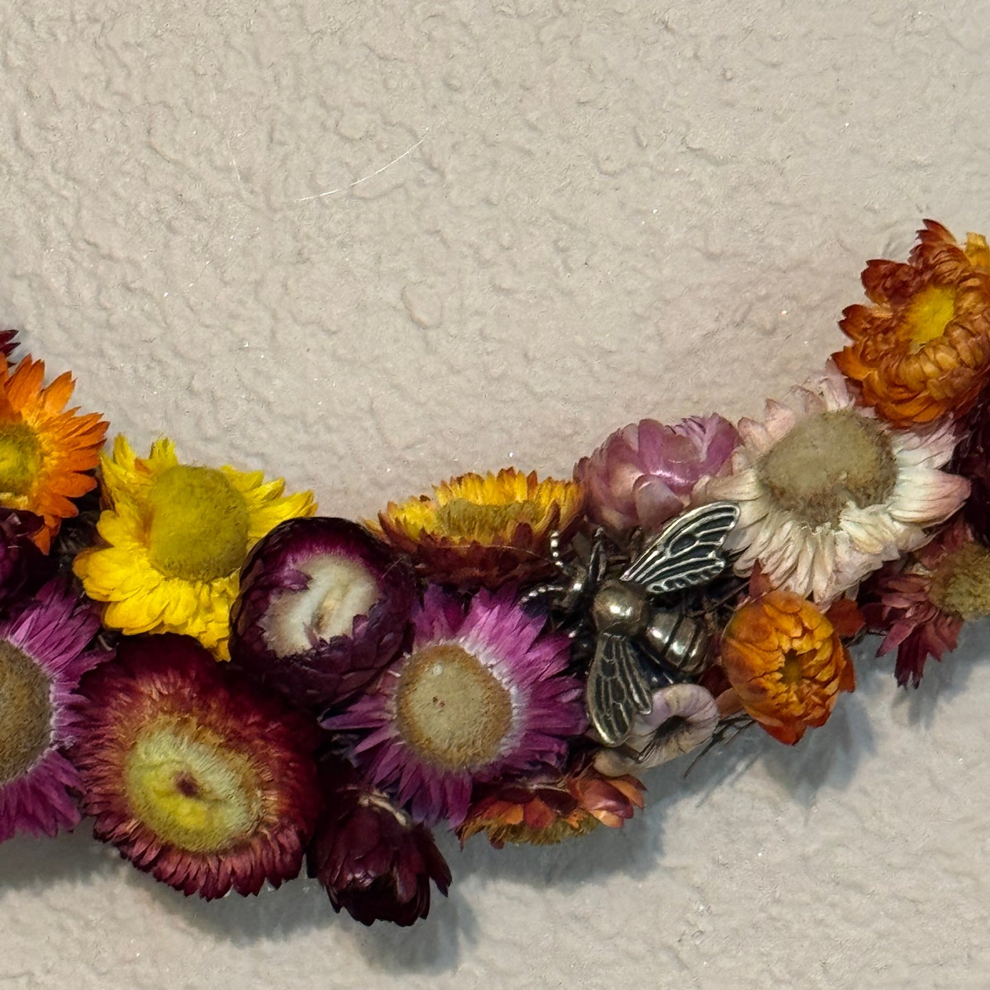Decorative letter 'I' made of dried flowers on a textured white background