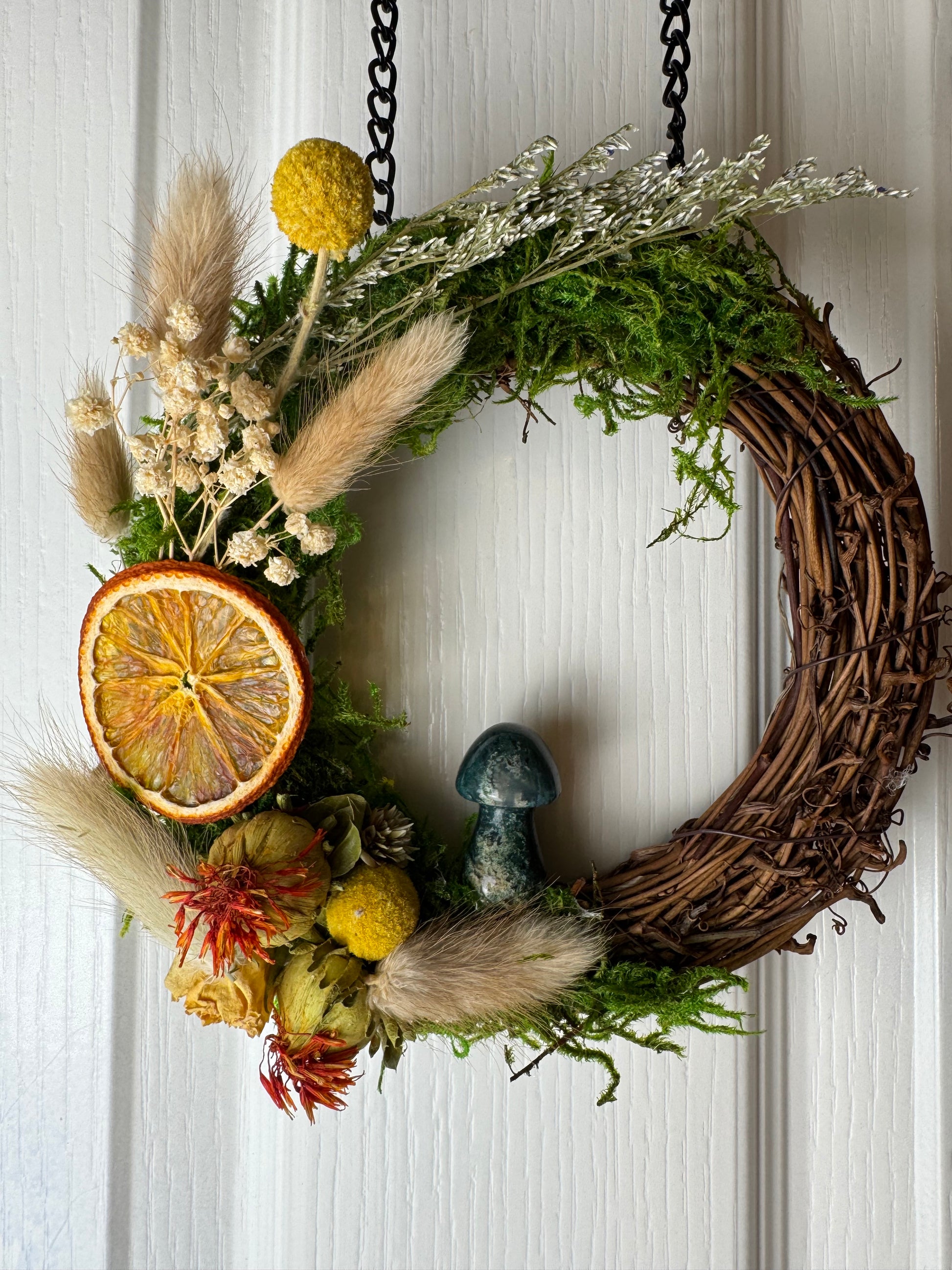 Decorative wreath with dried flowers and oranges on a white background