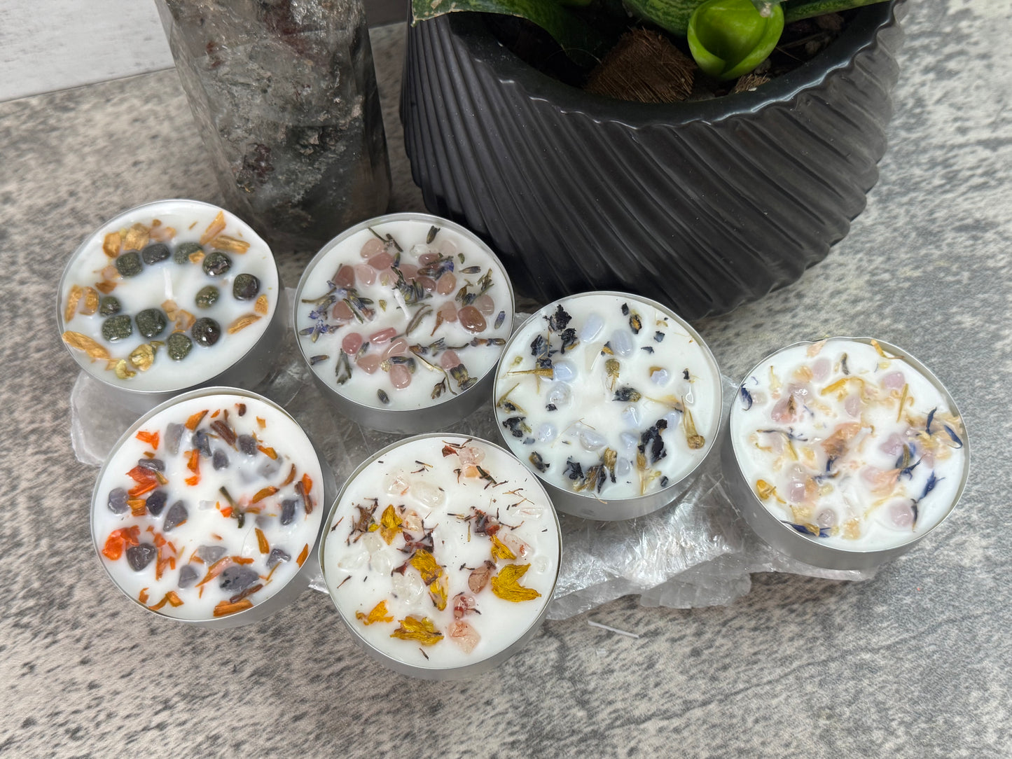 Set of decorative candles with embedded stones on a stone surface.