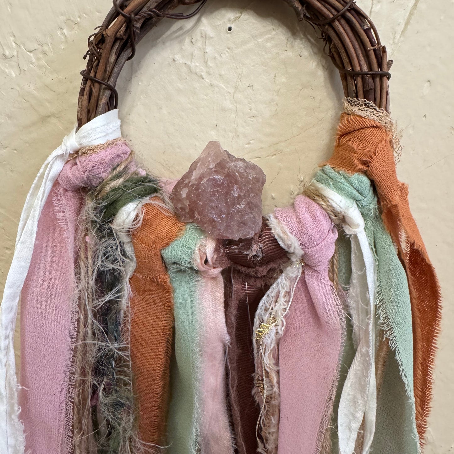 Textile art piece with fabric layers and a woven base on a neutral background