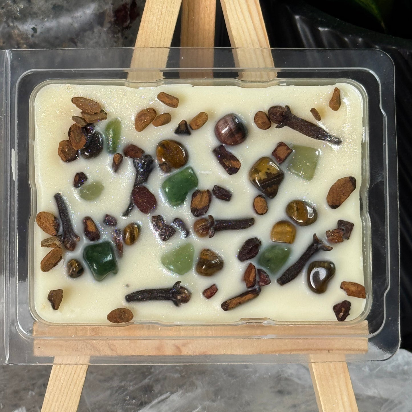 Square mold with white chocolate and assorted stones on a gray surface