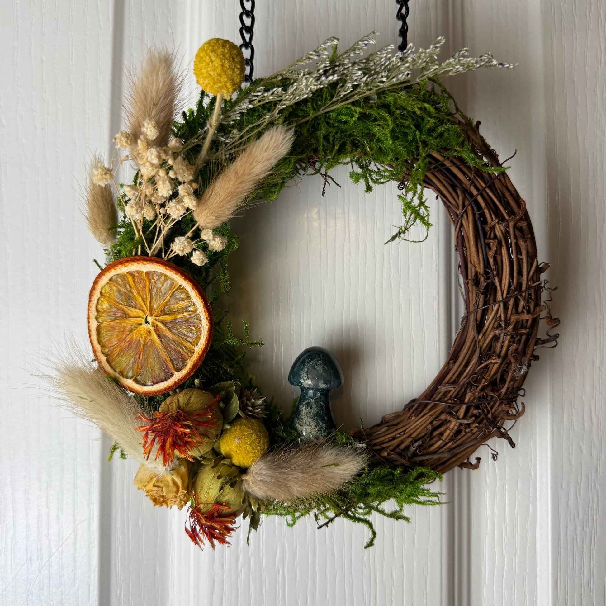 Decorative wreath with natural elements hanging on a white door.
