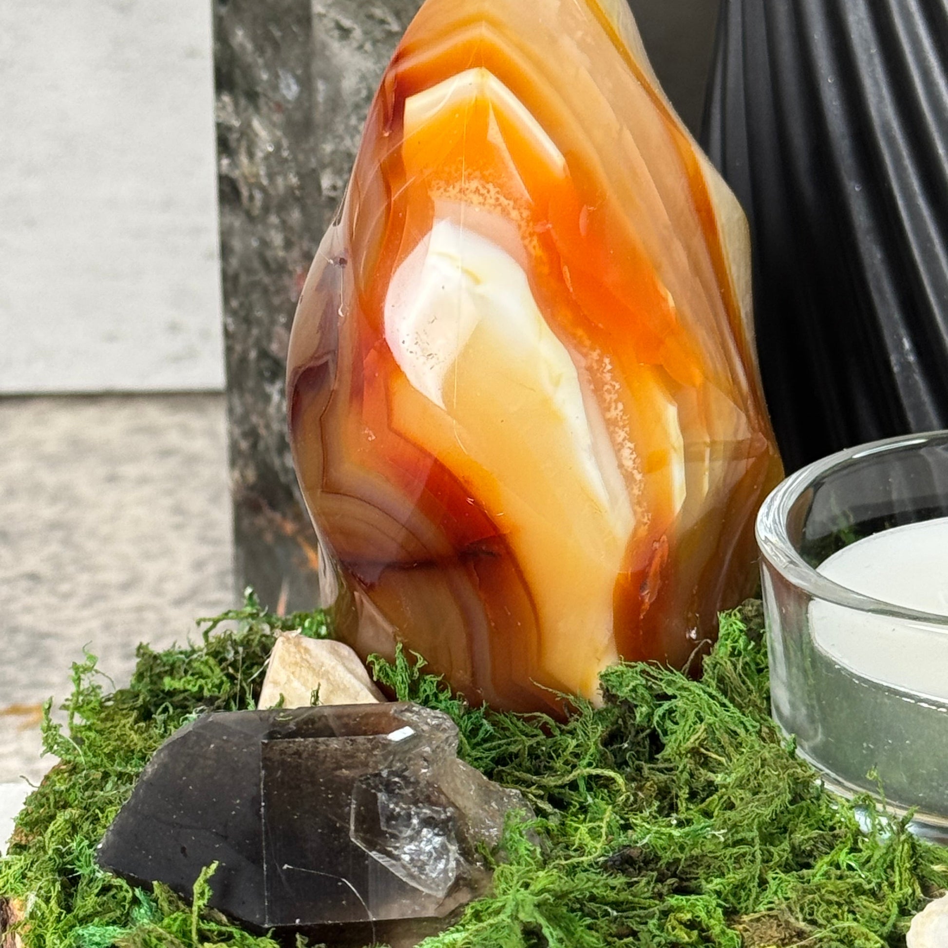 Polished agate stone with a glass container and moss in the background