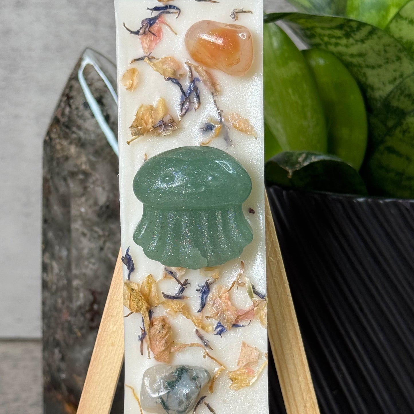 Decorative stone with natural elements on a stand, plant in the background