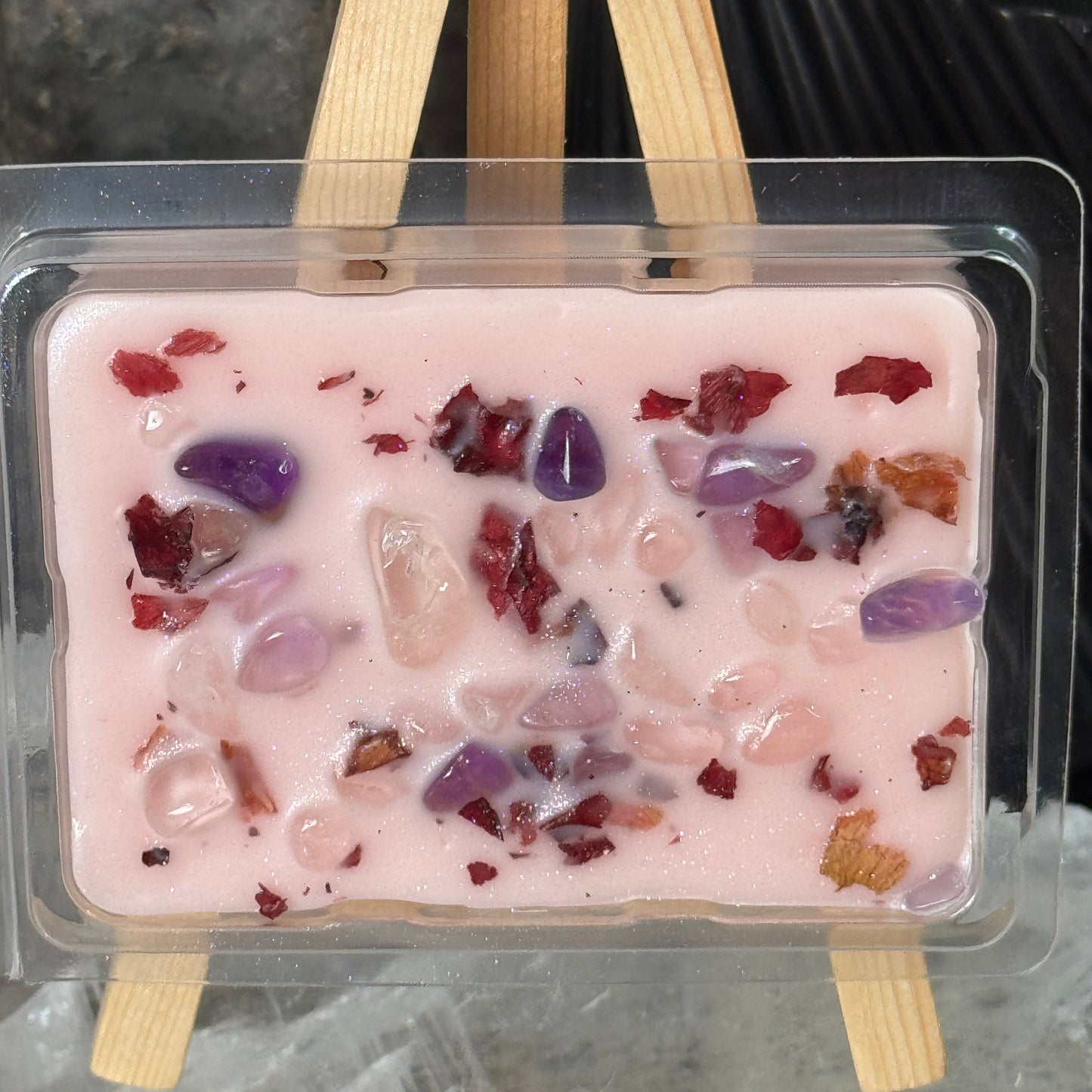 Popsicle mold with pink popsicle mixture and visible ingredients on a gray surface