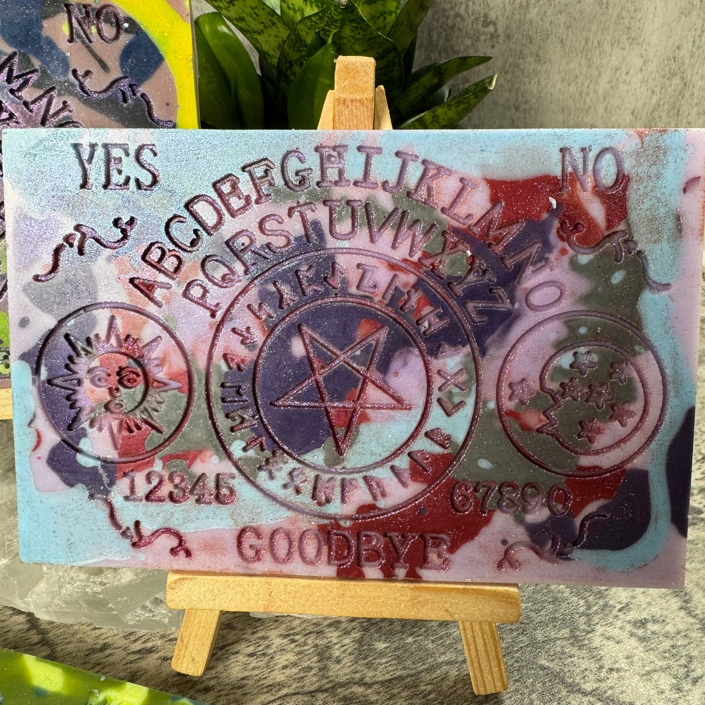 Decorative card with symbols and text on a stand, with a plant in the background