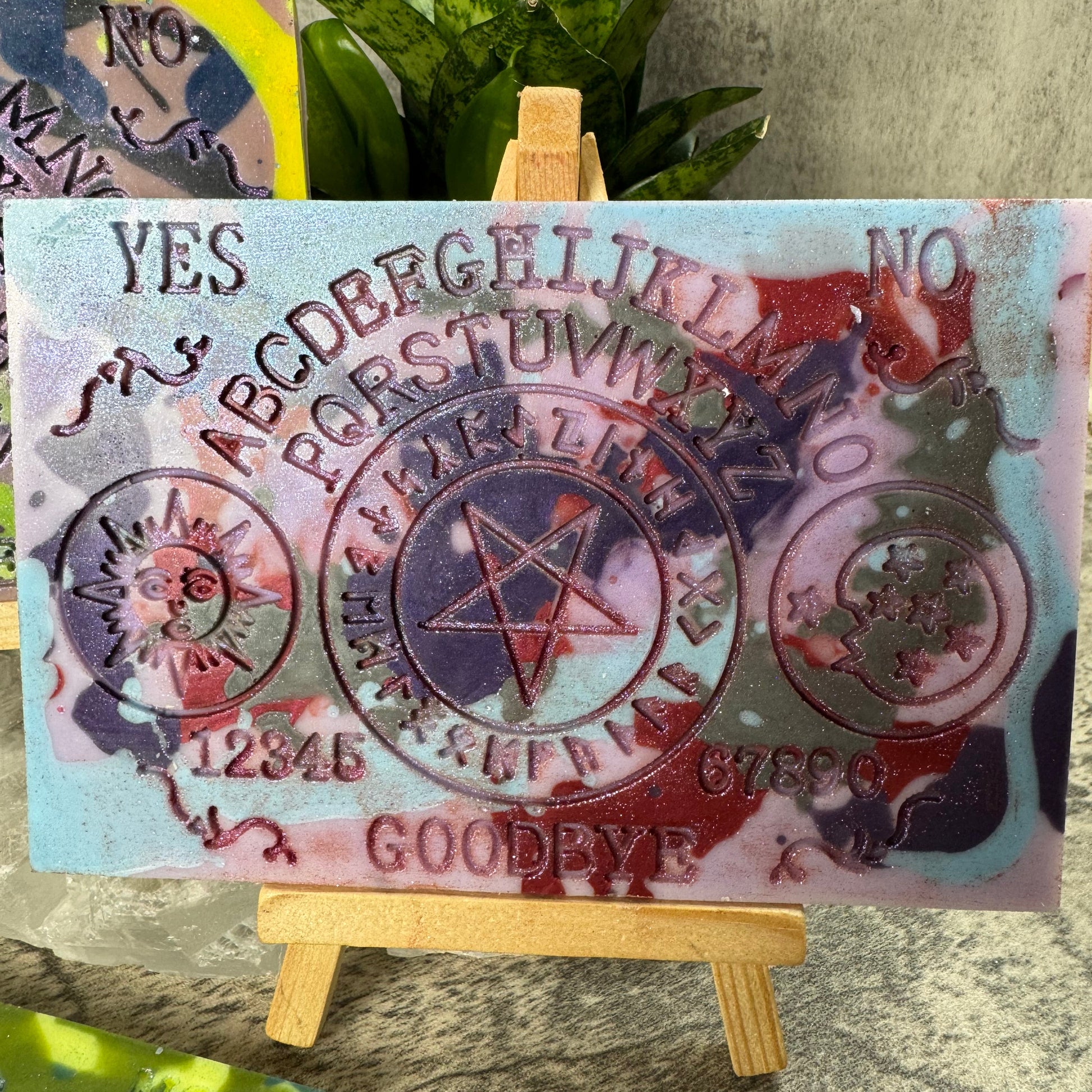 Decorative card with symbols and text on a stand, with a plant in the background