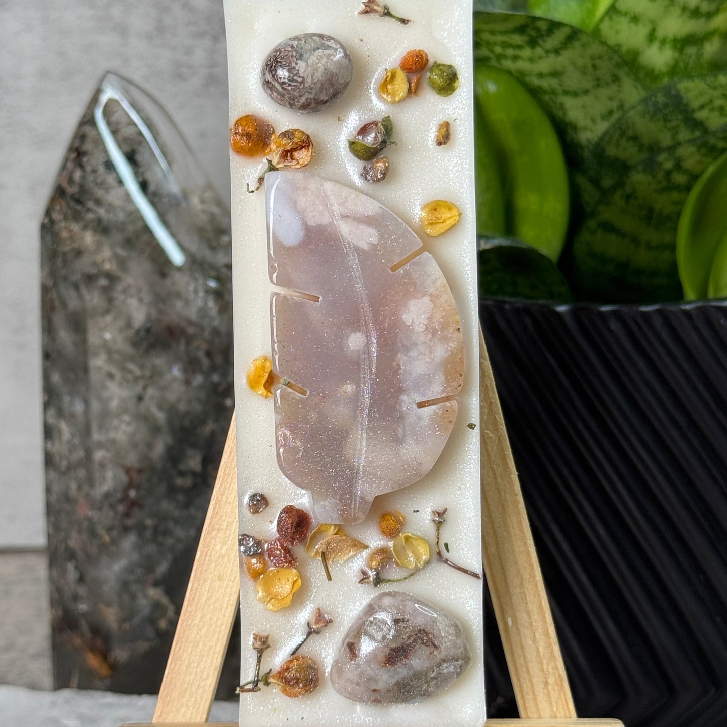 Decorative stone with natural elements on a stand, with a plant in the background
