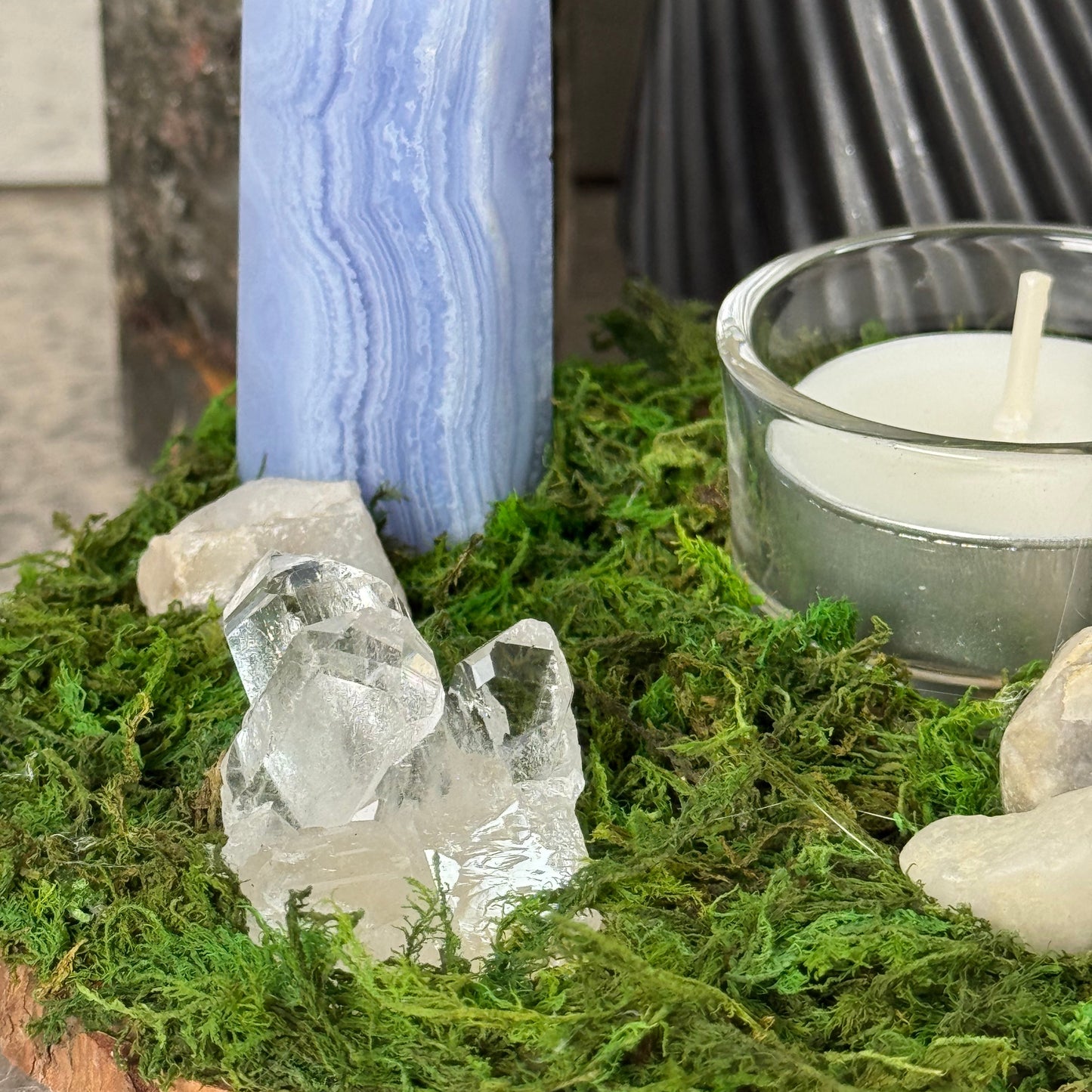 Crystal and moss arrangement with a candle on a stone surface