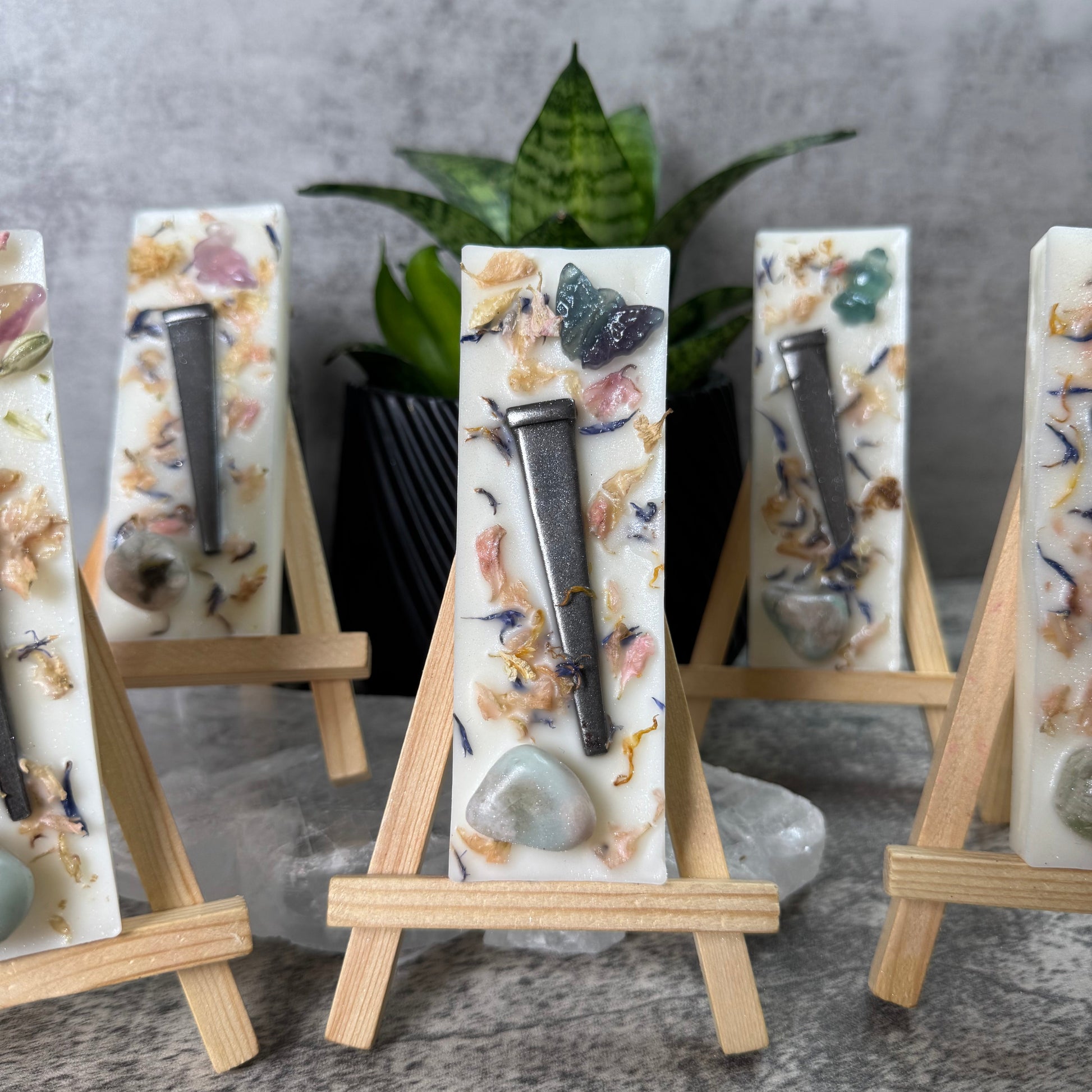 Decorative soap bars with natural elements on a stand against a neutral background