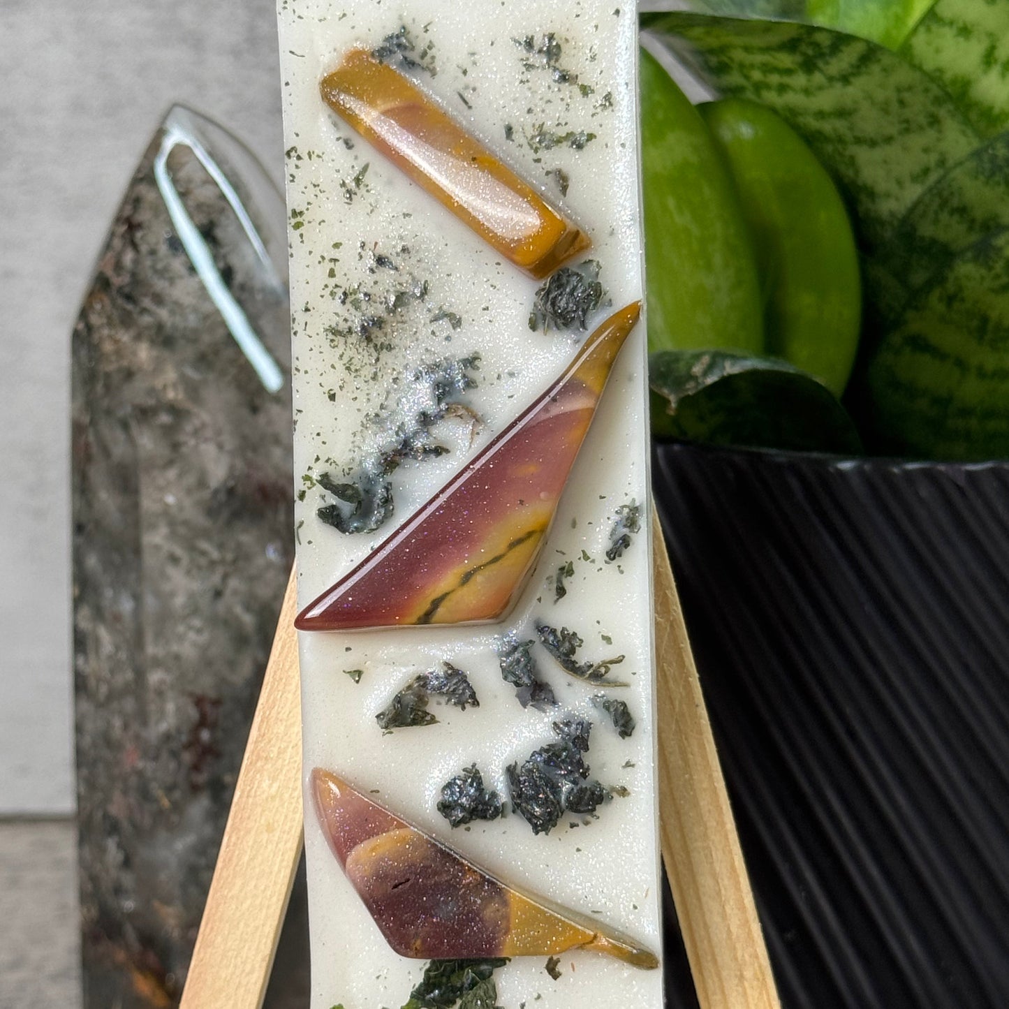 Decorative soap bar with natural elements on a wooden stand, placed on a stone surface.