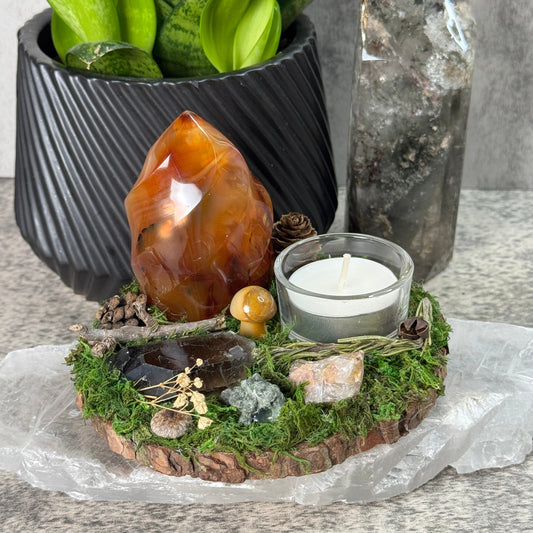 Decorative arrangement with crystals, candle, and plants on a stone surface