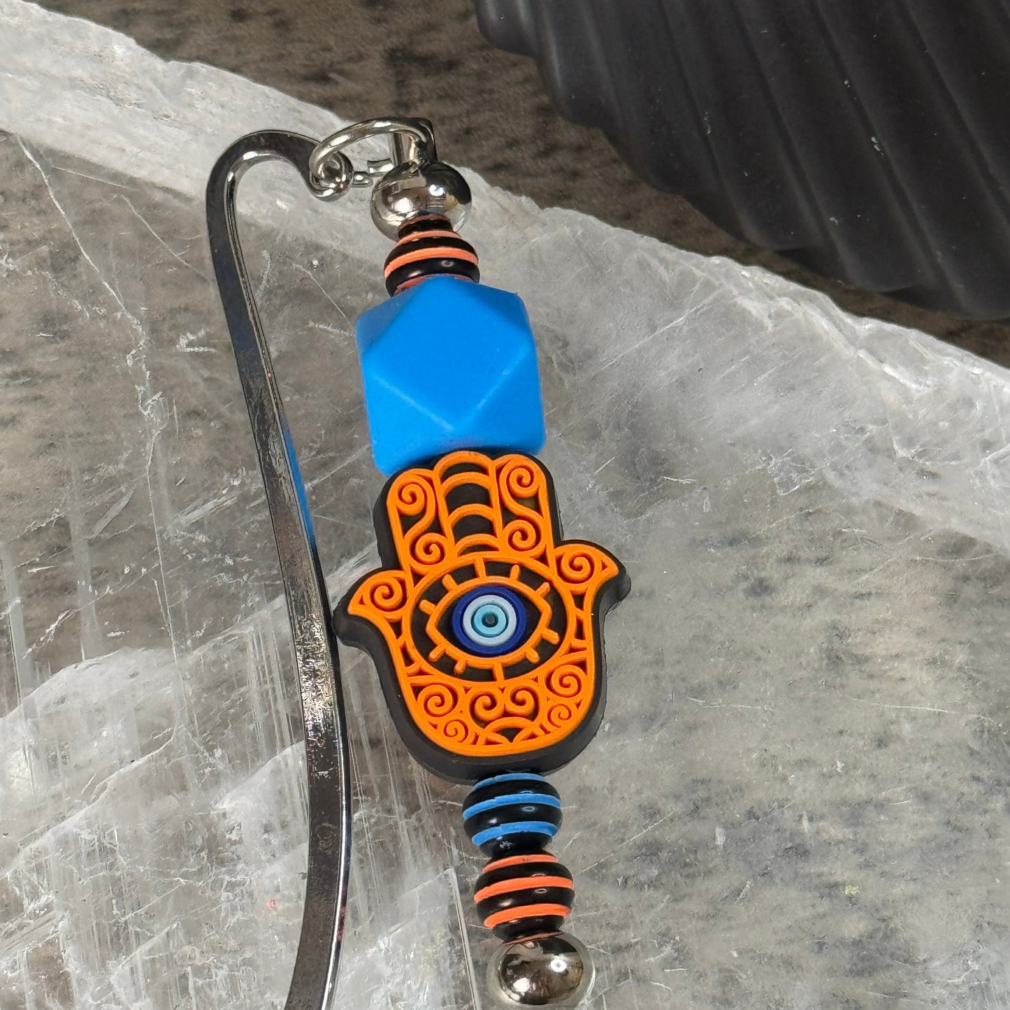 Decorative keychain with Hamsa hand design on a textured surface
