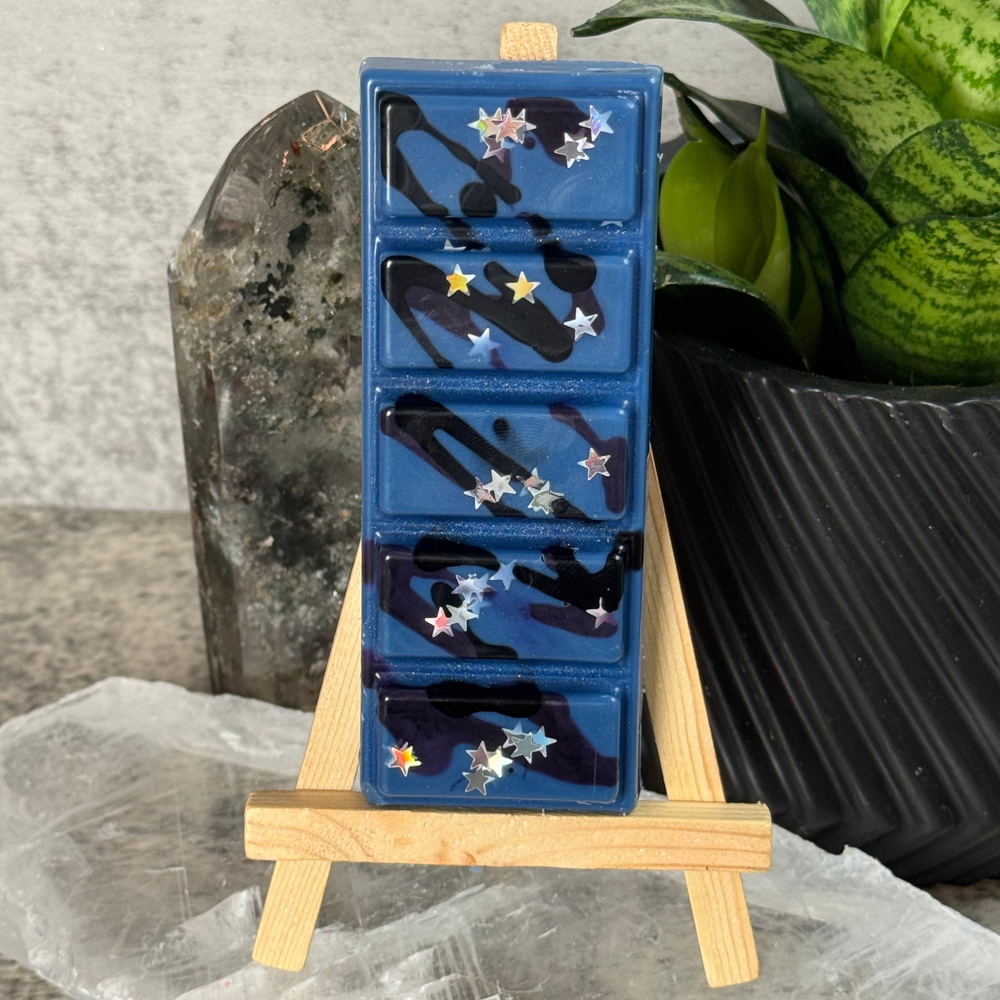 Blue wax melt tray with decorative elements on a wooden stand, placed on a marble surface.