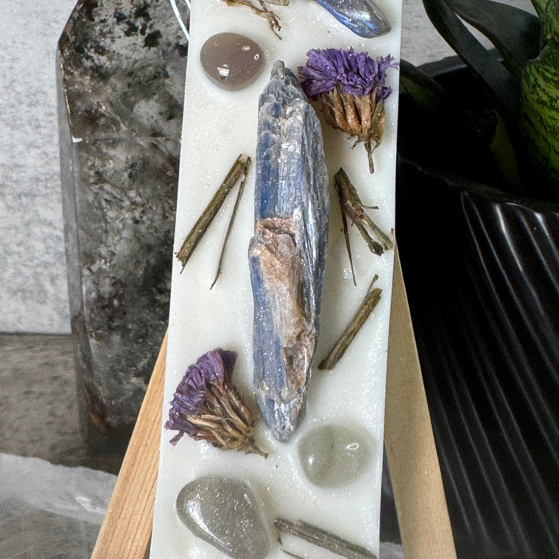 Decorative stone with seashell, pebbles, and dried flowers on a marble slab.