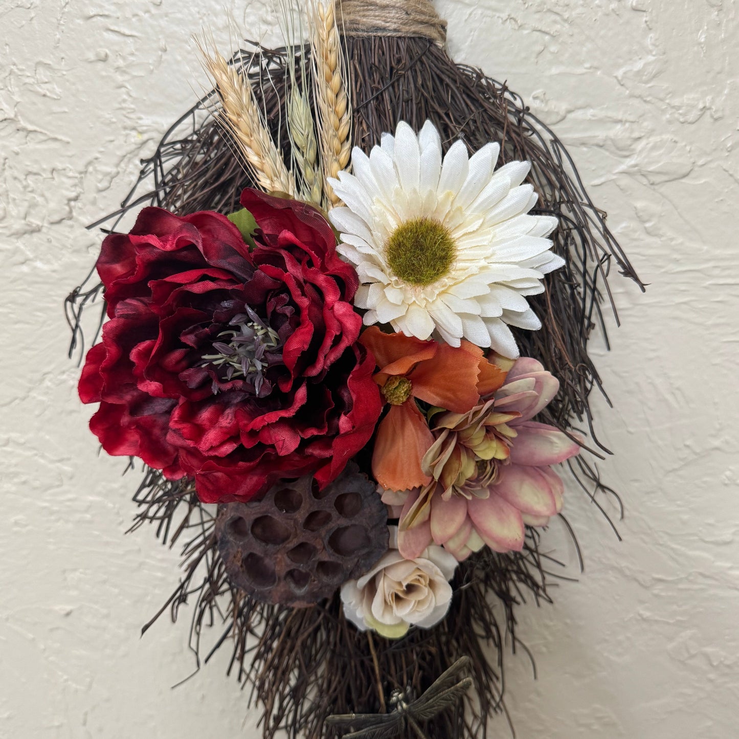 Decorative wreath with flowers and twigs on a textured wall