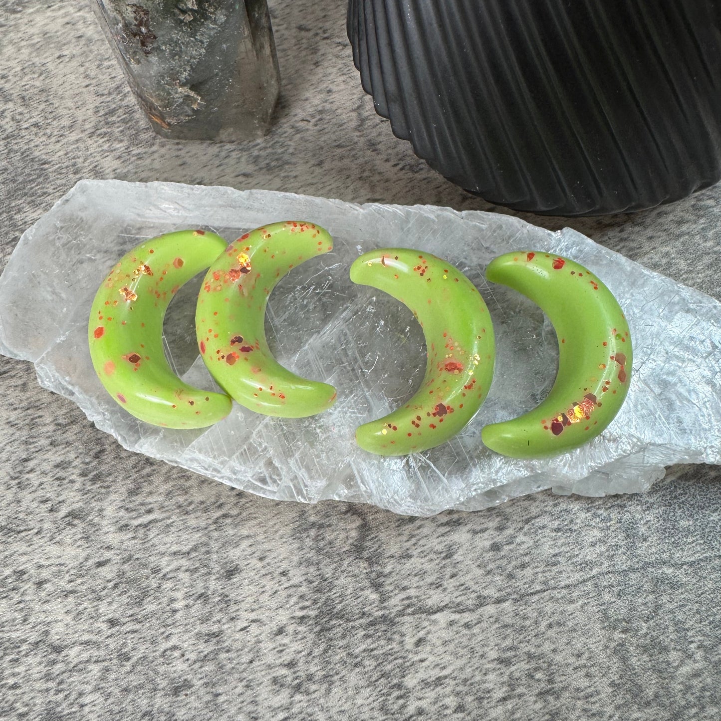 Three green crescent-shaped objects on a translucent paper over a gray surface.