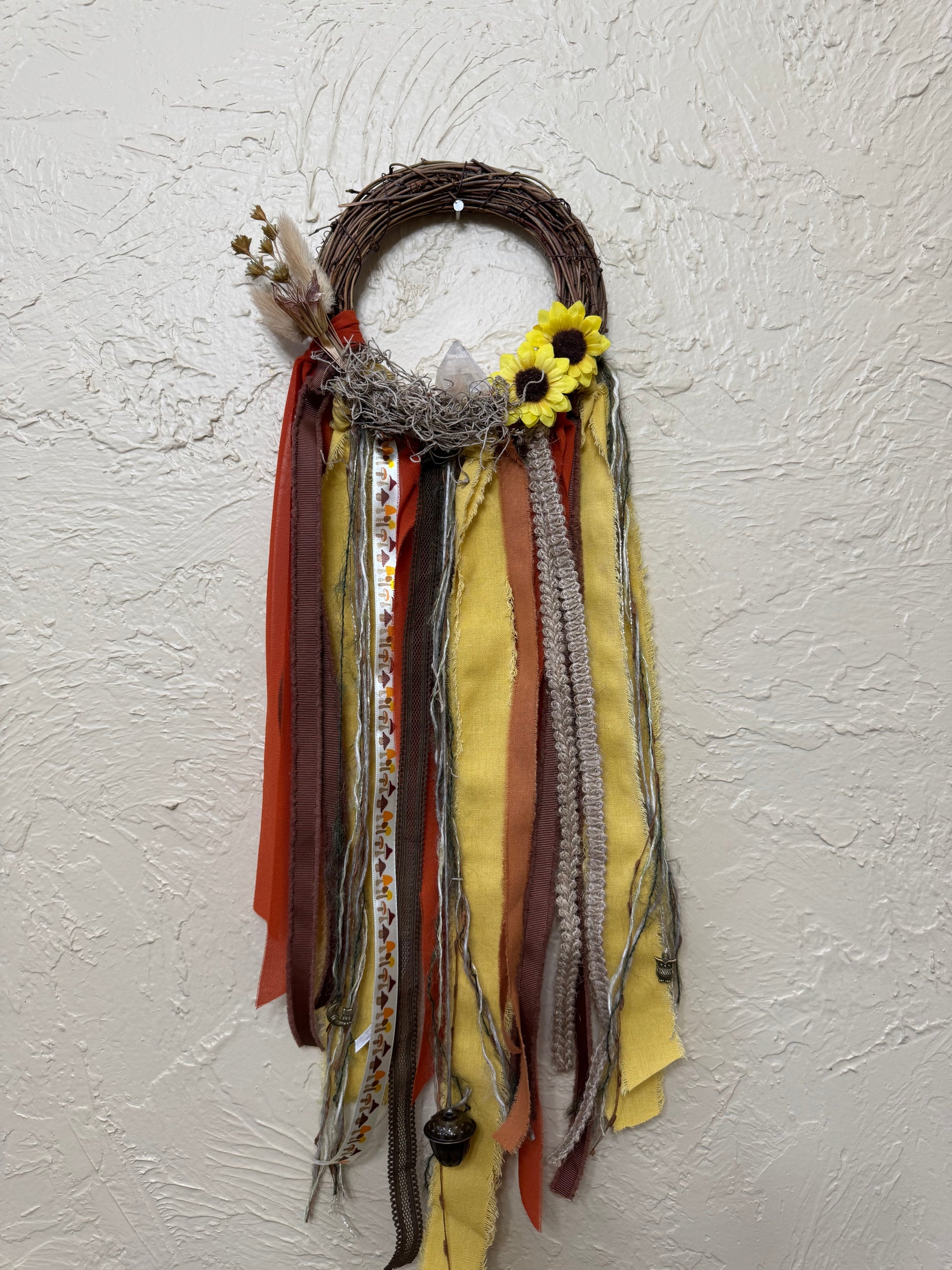 Decorative wreath with ribbons and a sunflower on a textured wall