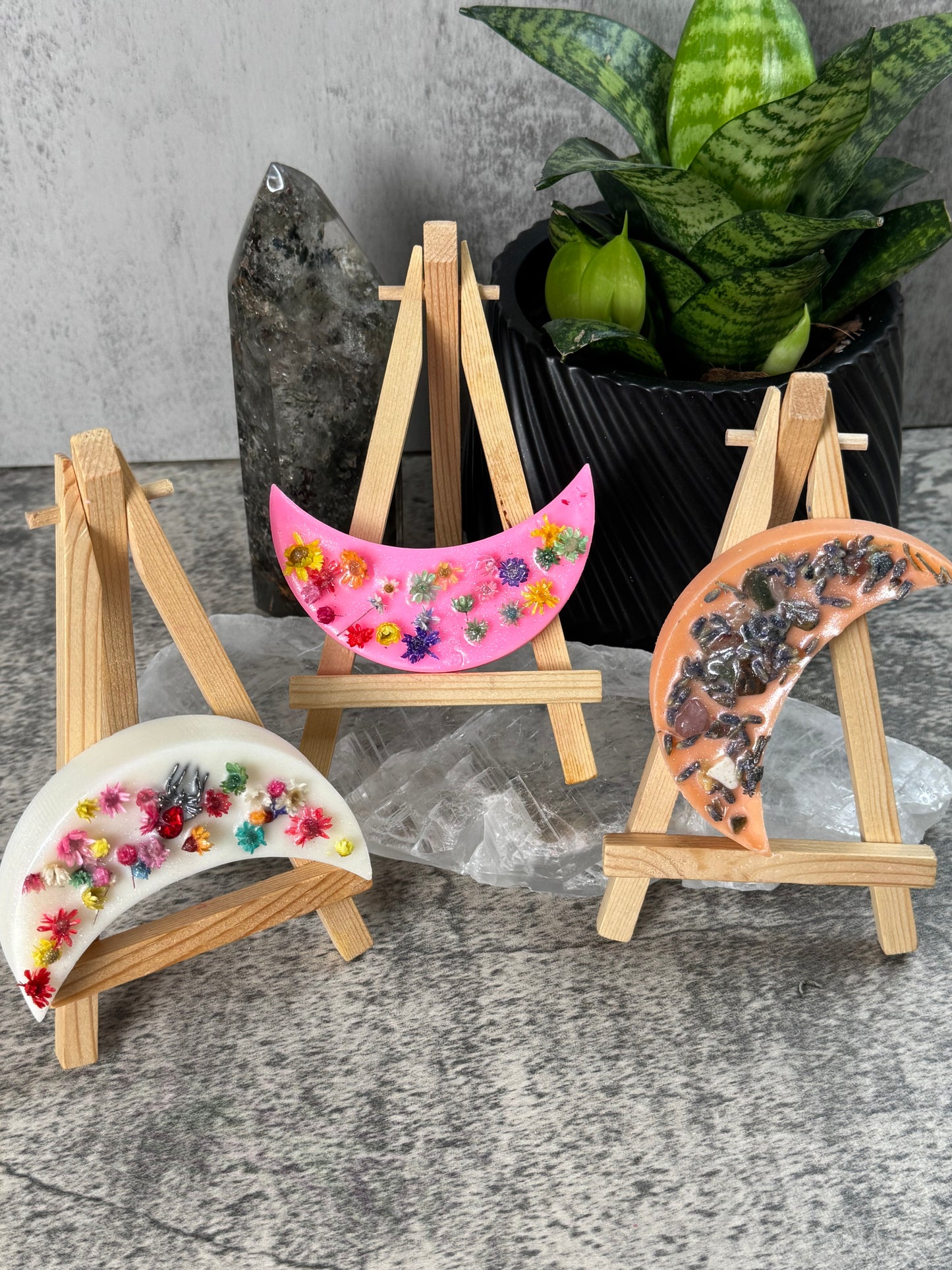 Decorative half-moon plates with floral designs on a stand against a gray background.