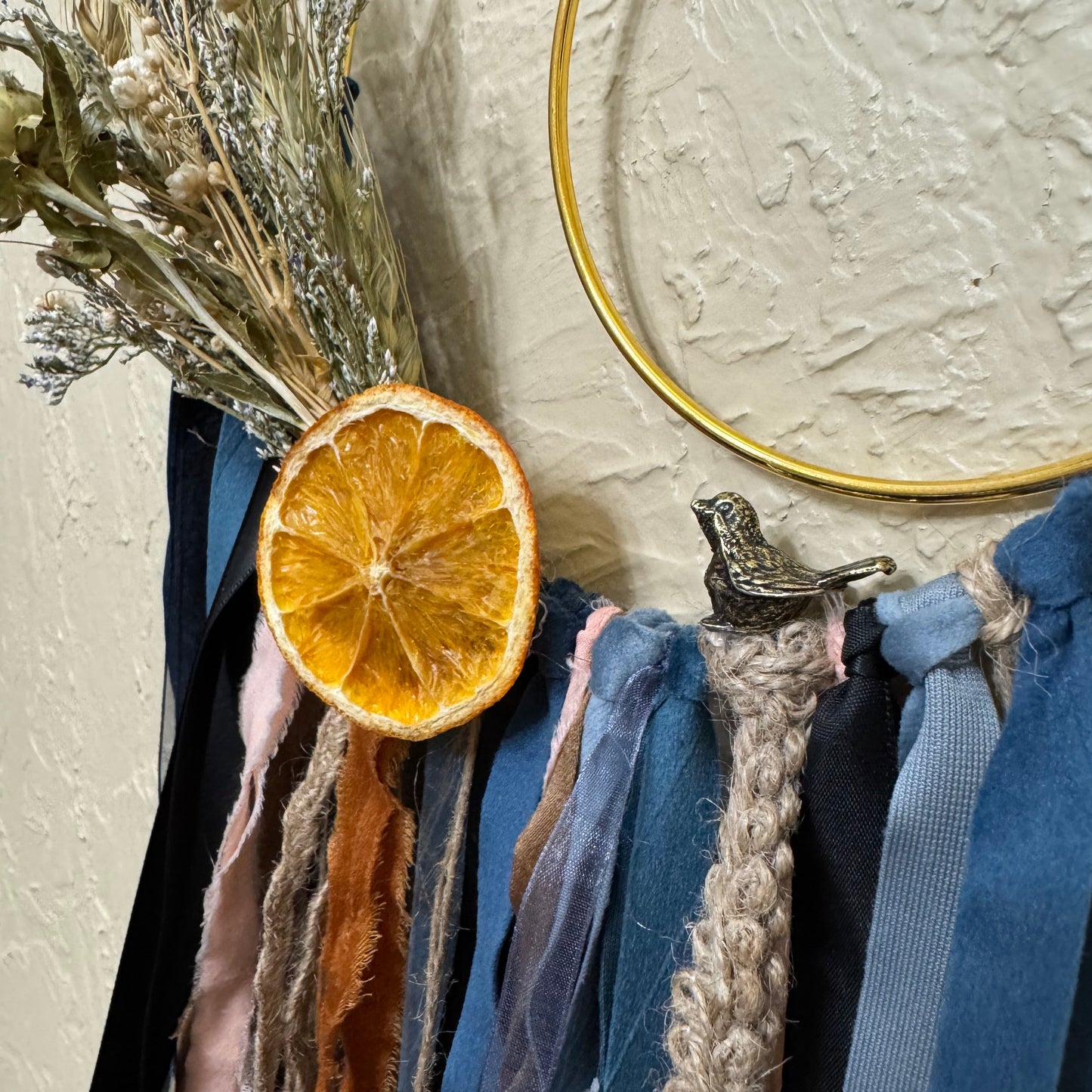 Stack of folded clothes with a dried orange slice and gold ring on a textured surface