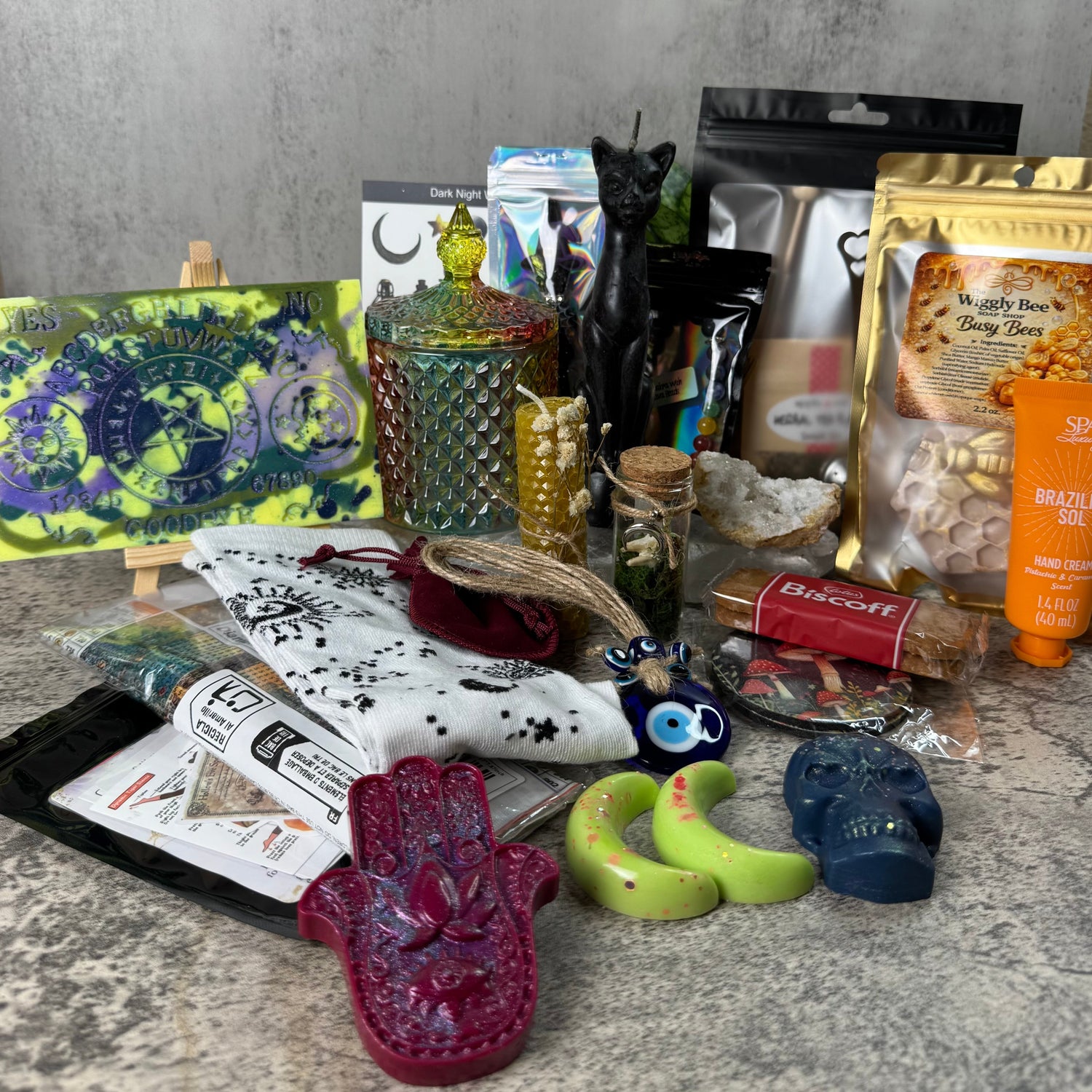 Assorted items including a Hamsa hand, candles, and packaging on a textured surface.