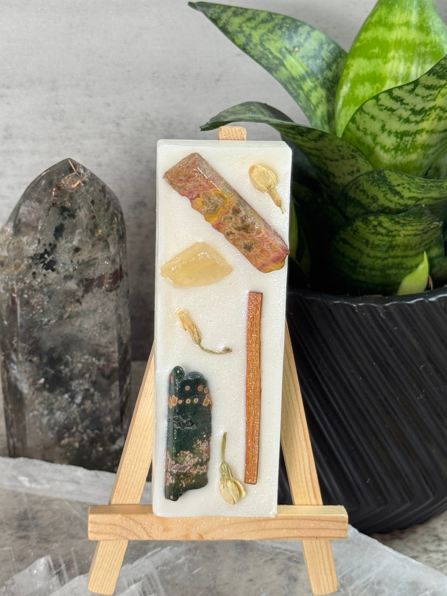Decorative stone with embedded natural elements on a wooden stand, set against a neutral background.