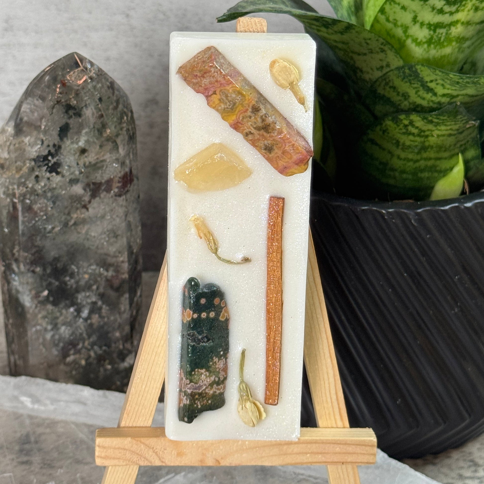 Decorative stone with embedded natural elements on a wooden stand, set against a neutral background.
