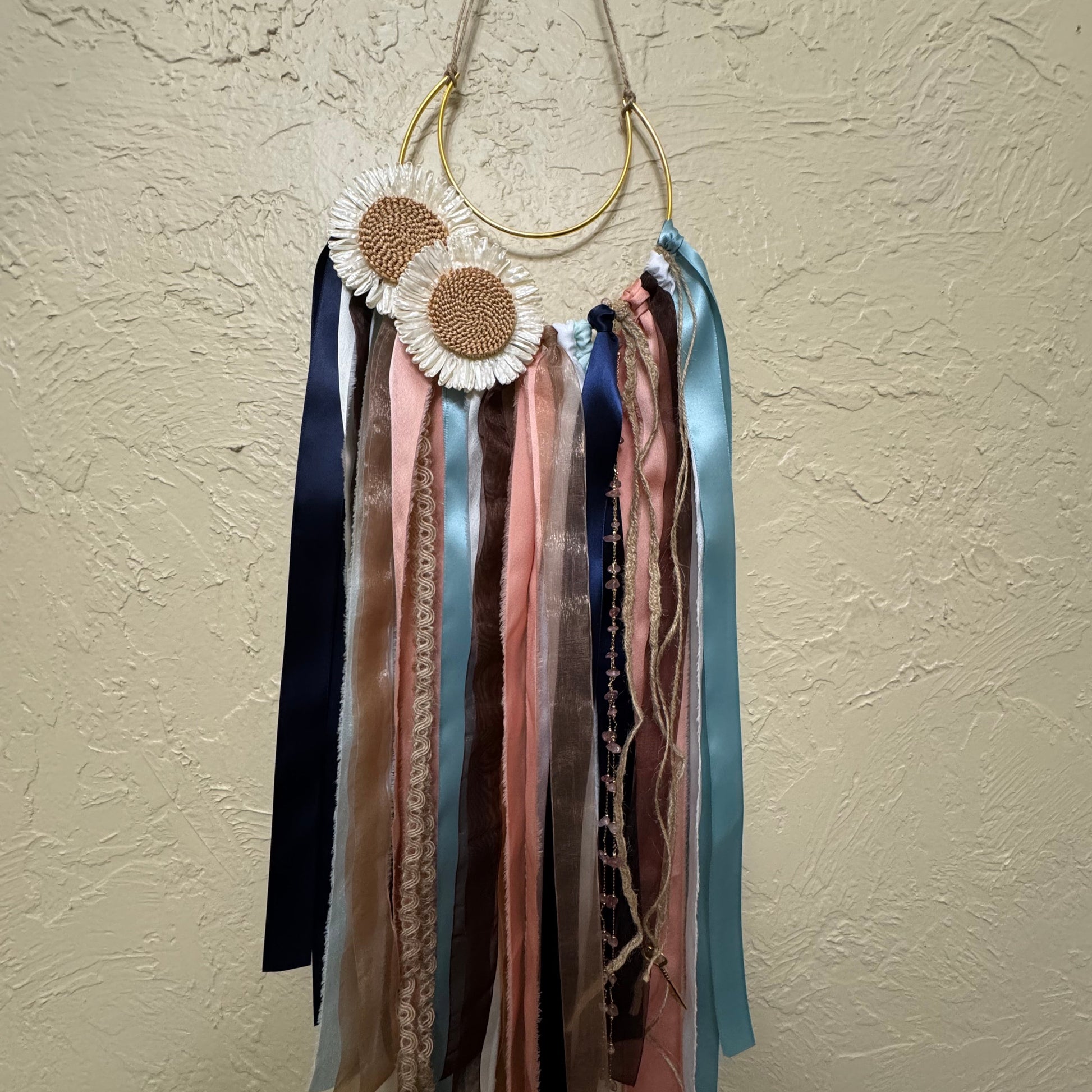 Decorative earrings with colorful ribbons on a beige wall