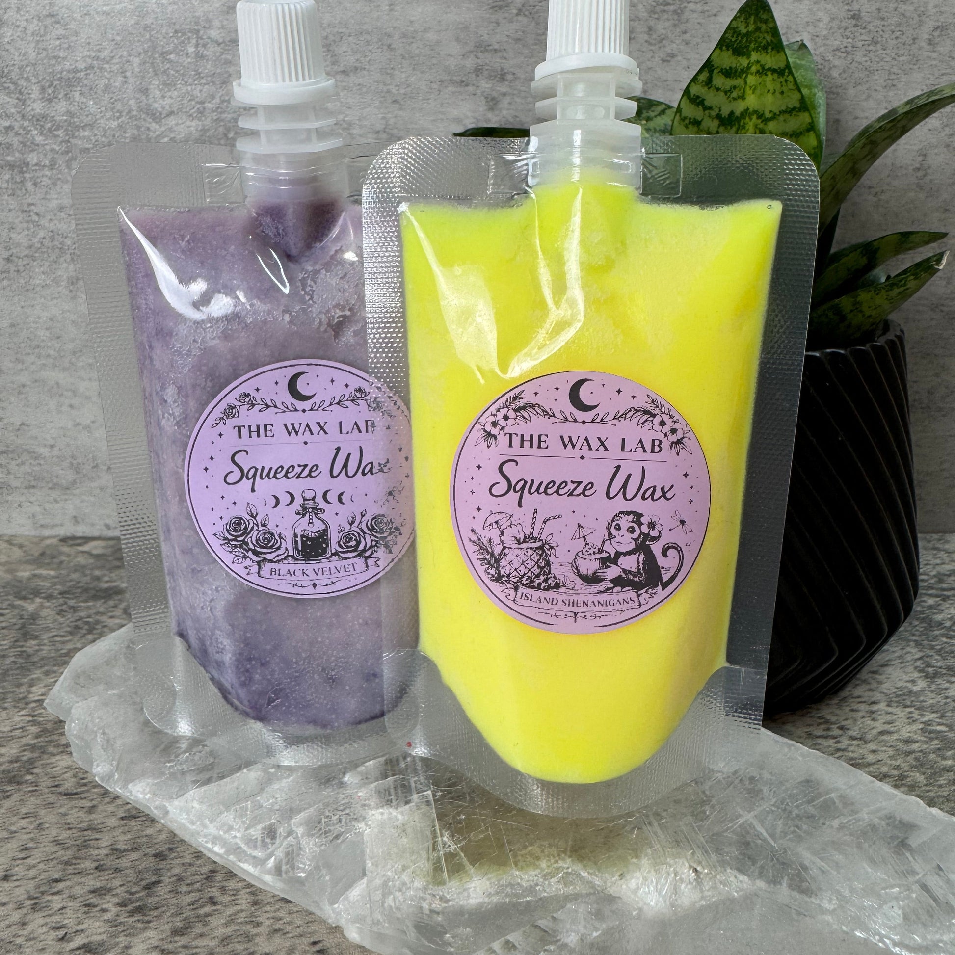 Two squeeze bottles, one yellow and one purple, with labels on a gray surface.