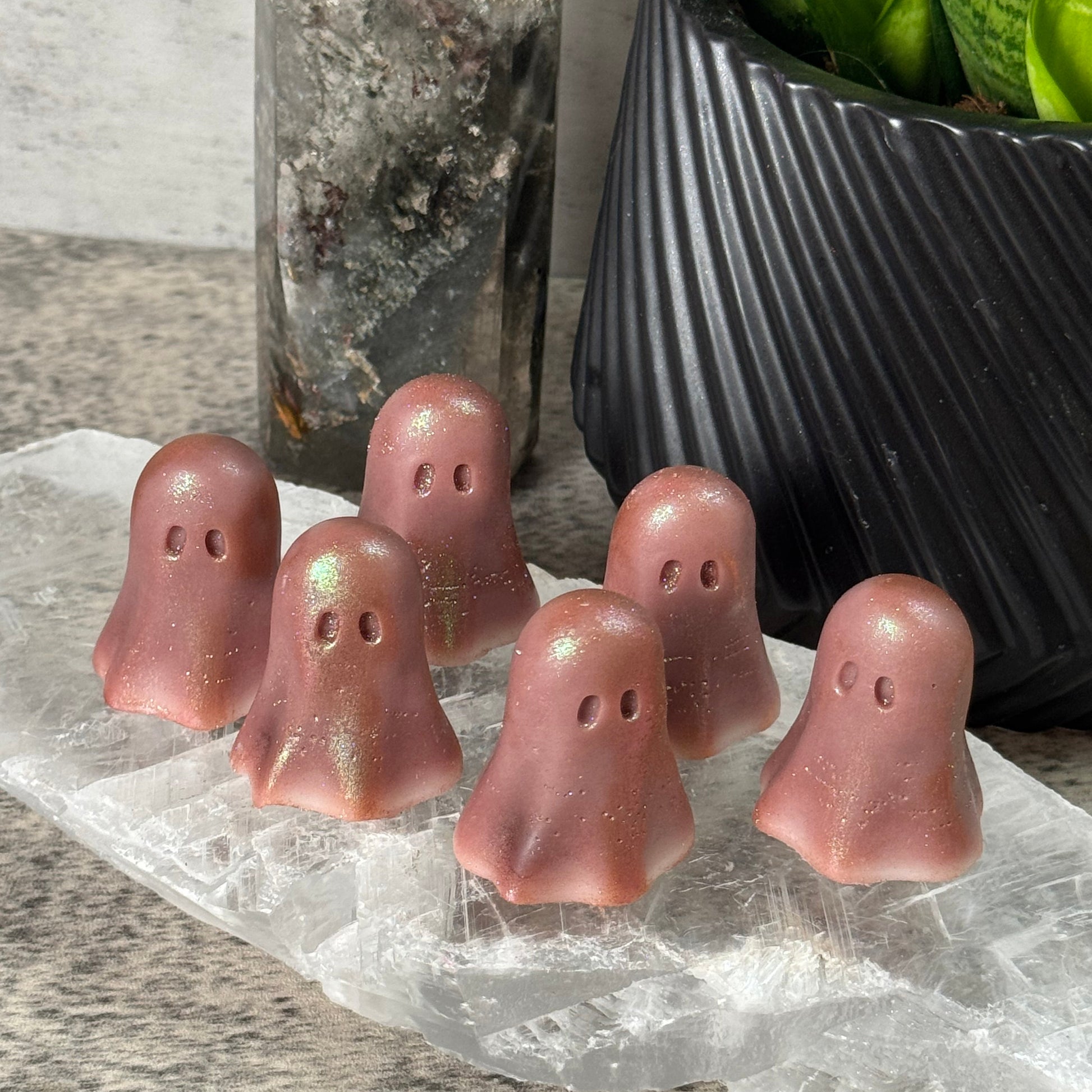 Pink silicone earbuds on a clear plastic sheet with green plants in the background