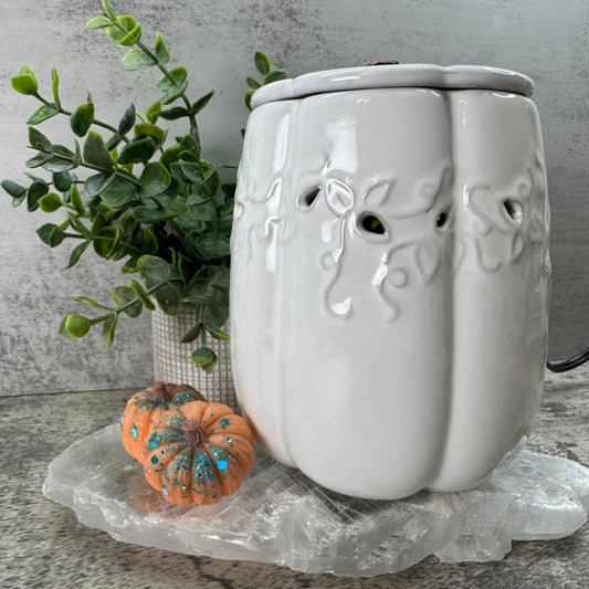 White ceramic wall-mounted diffuser with decorative elements on a textured surface