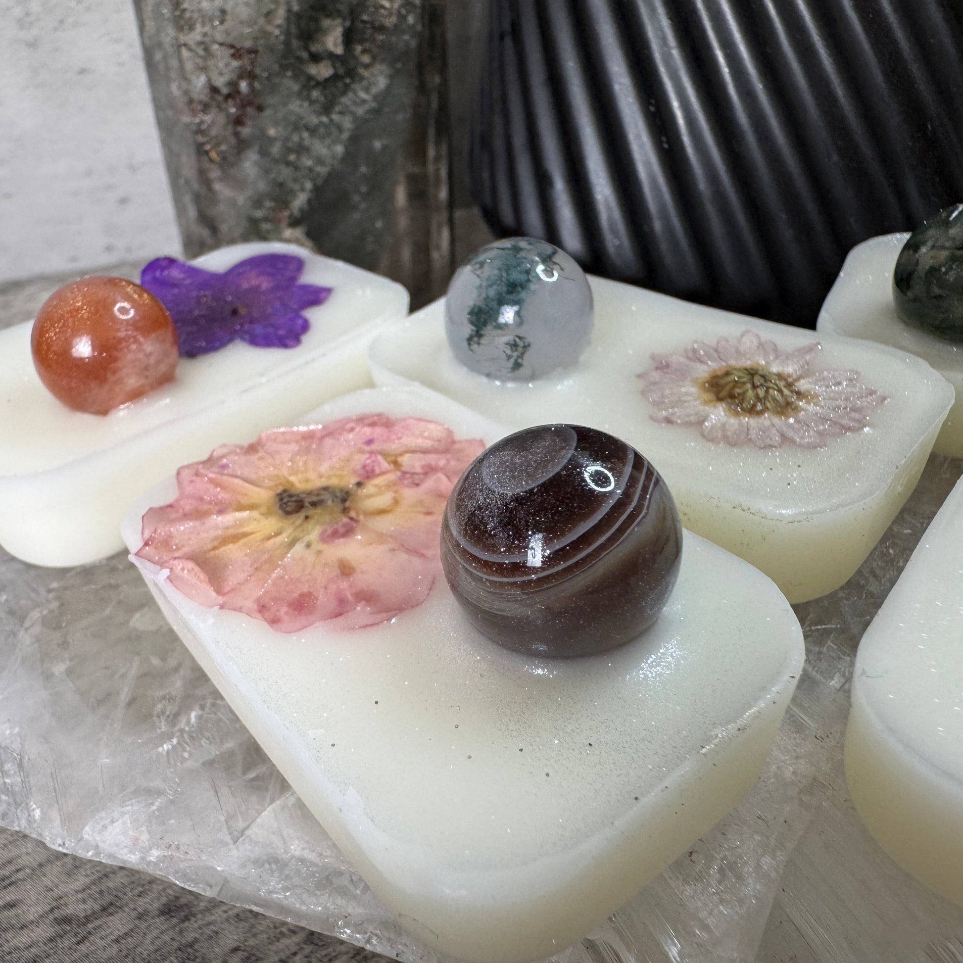 White soap bars with embedded stones and flowers on a textured surface