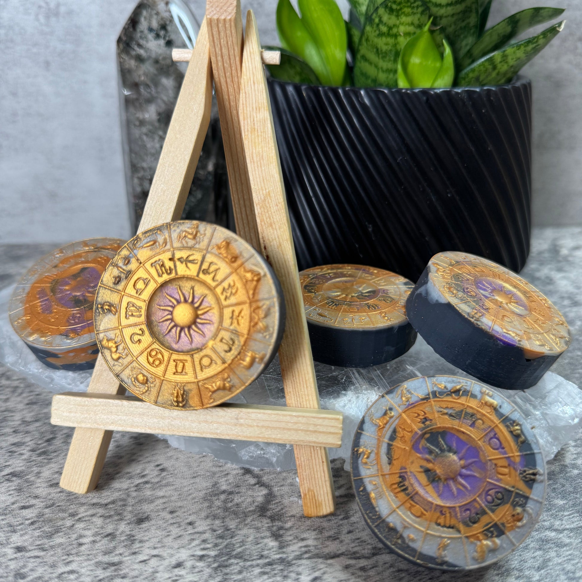 Decorative items including a black bowl, wooden sticks, and circular decorative objects on a textured surface with a plant in the background.