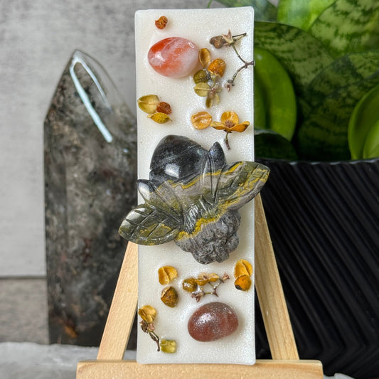 Decorative stone with a butterfly and small stones on a stand, against a neutral background.