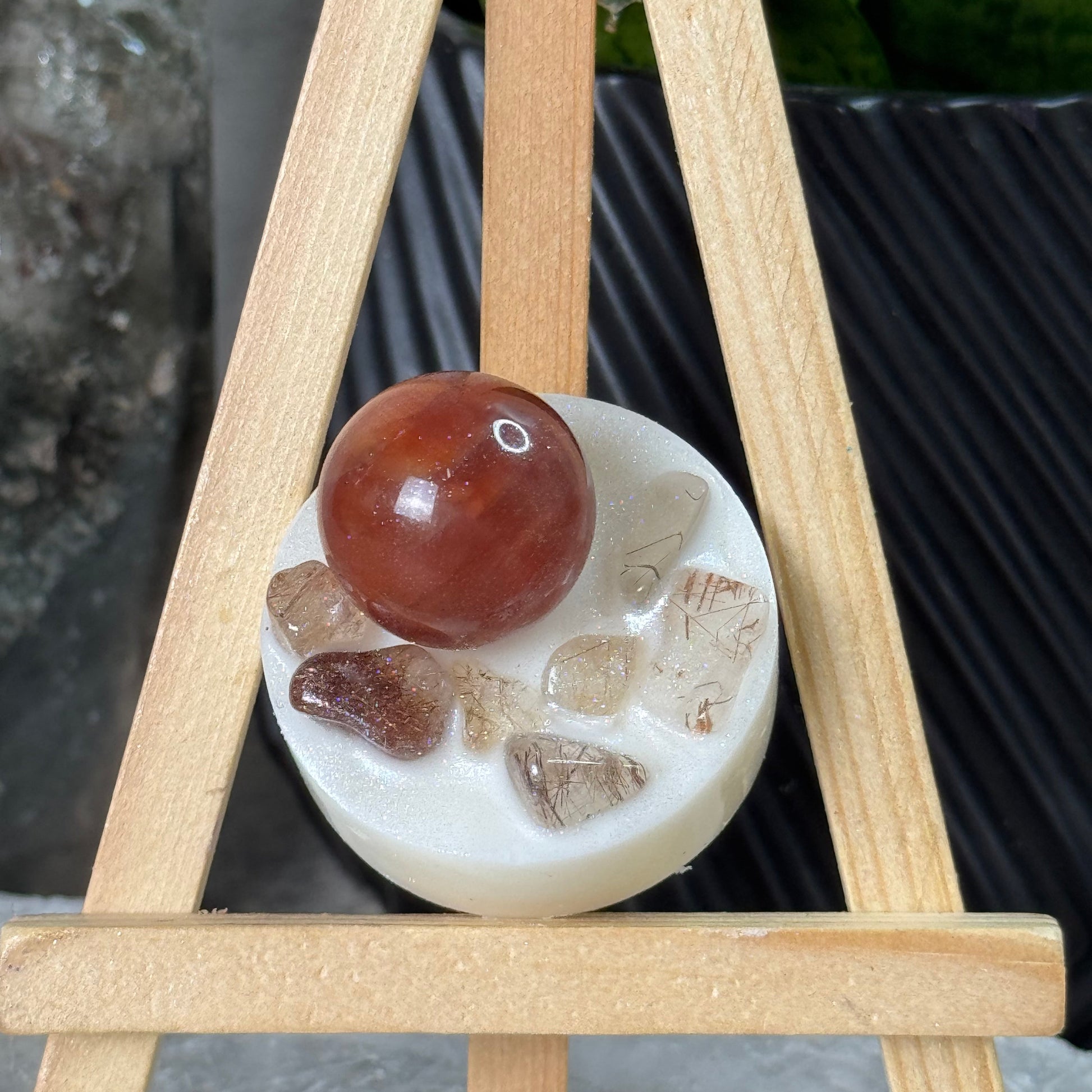 Round stone with embedded pieces on a wooden stand