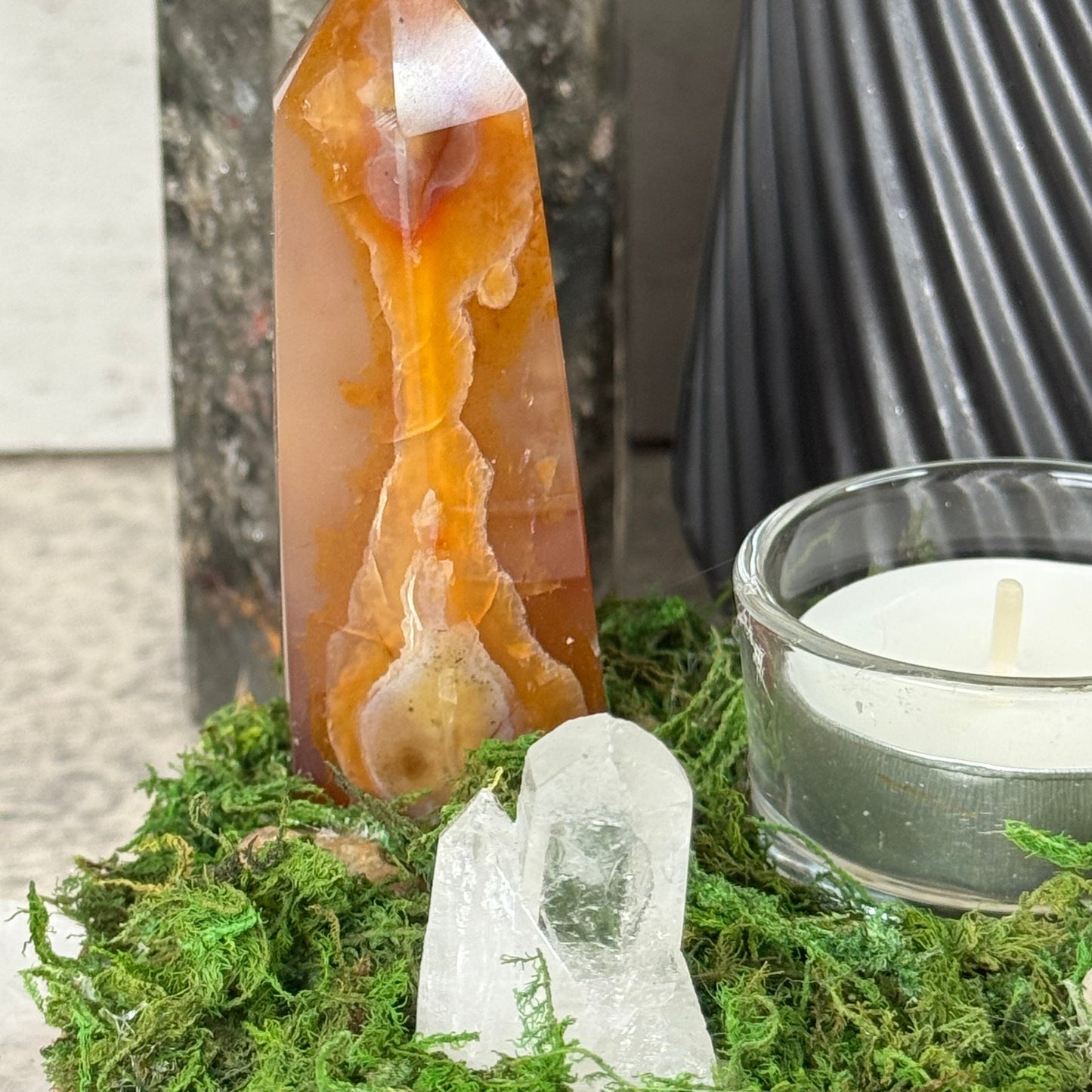 Crystal wand with a natural stone base on a green leafy background