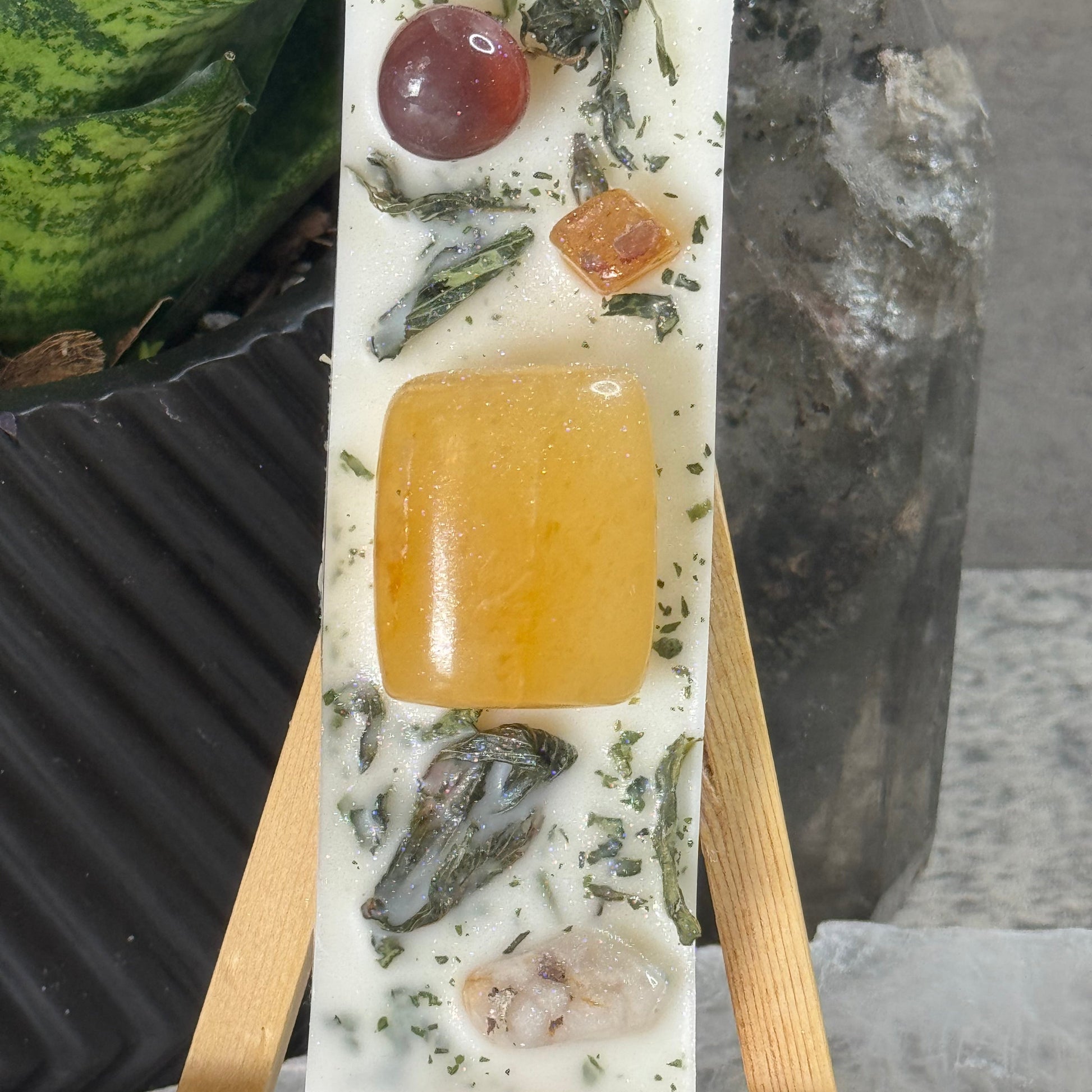 Rectangular soap with natural ingredients on a wooden stand against a stone background