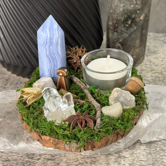 Decorative arrangement with a candle, stones, and a crystal on a stone surface
