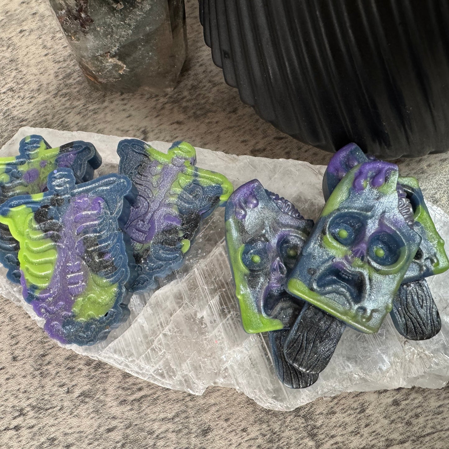 Two green and purple 3D-printed objects on a stone surface