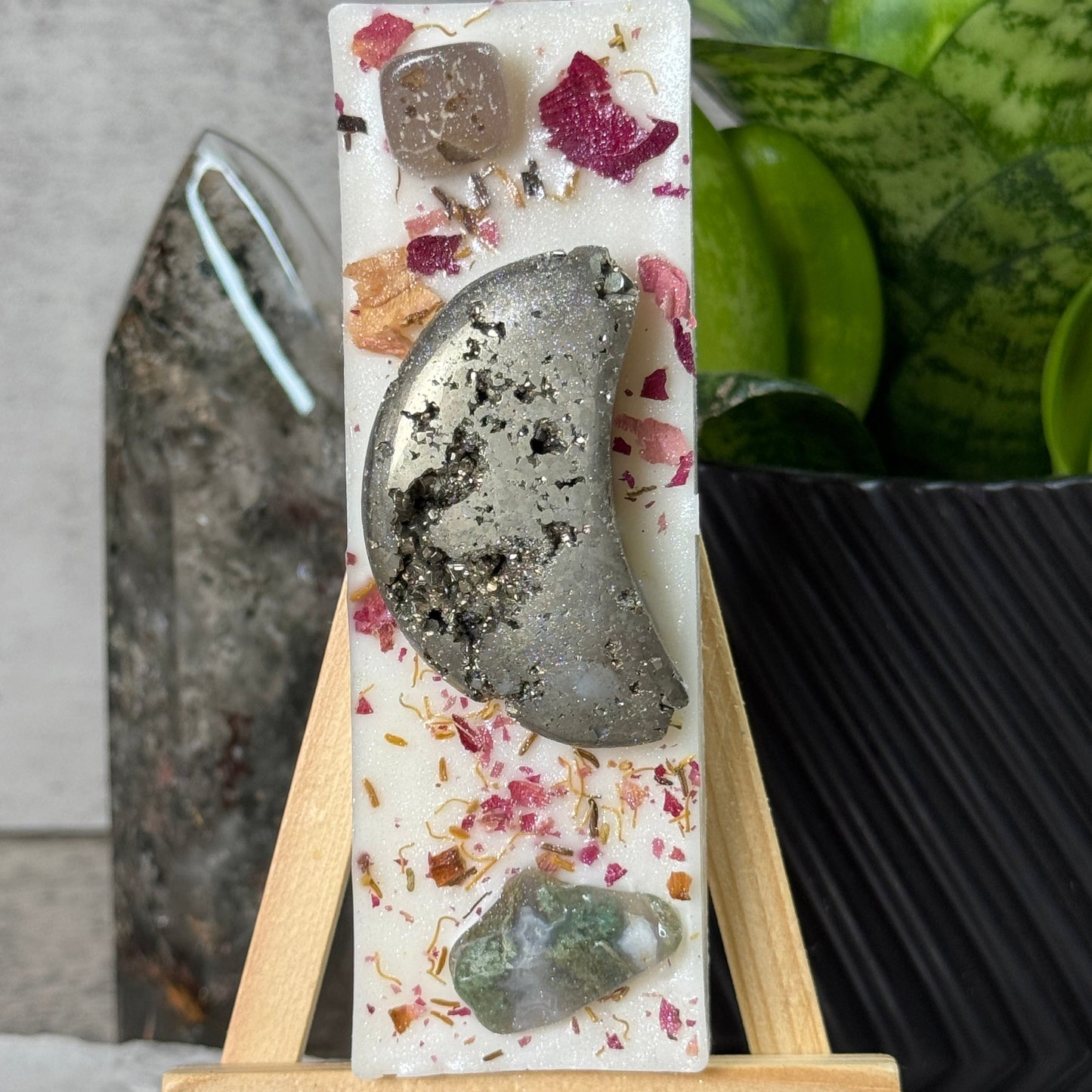 Decorative soap with natural elements on a stand, plant in the background